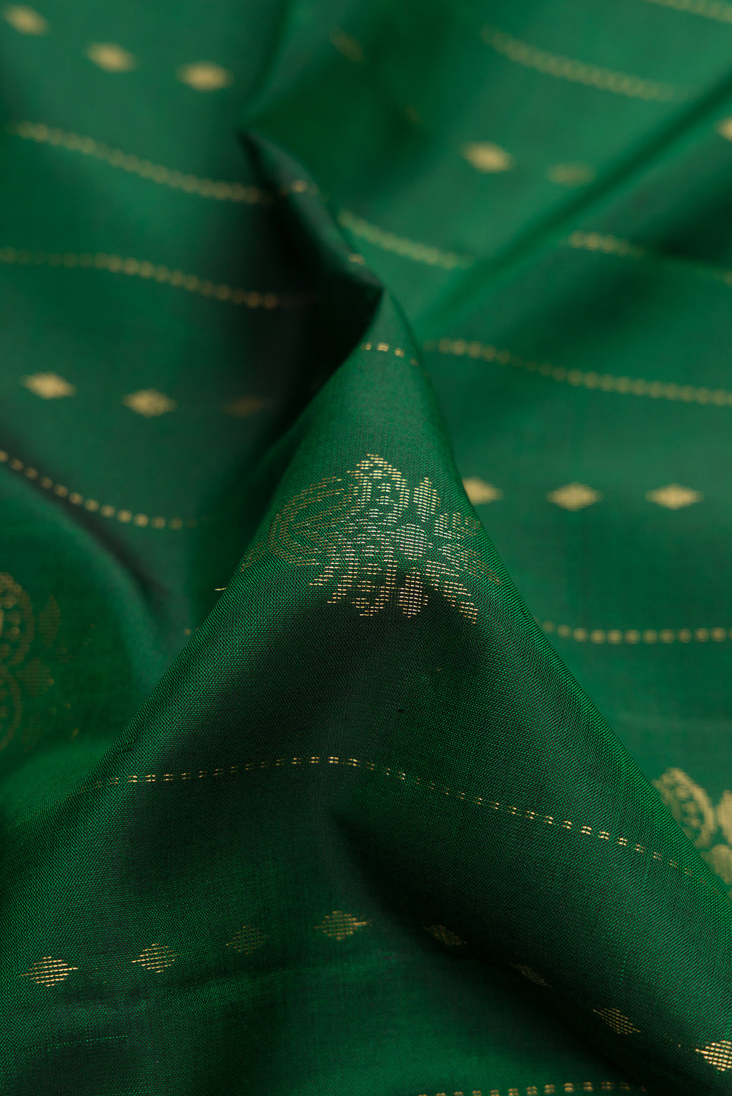 Close up of Green Dual Tone Soft Silk Saree with Zari Butta on the body and Zari Border.  displaying folds