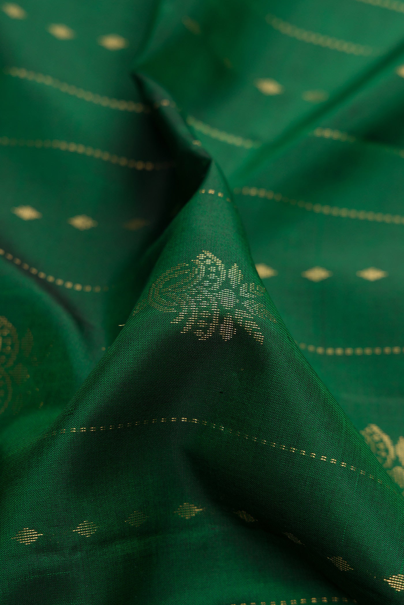 Close up of Green Dual Tone Soft Silk Saree with Zari Butta on the body and Zari Border.  displaying folds