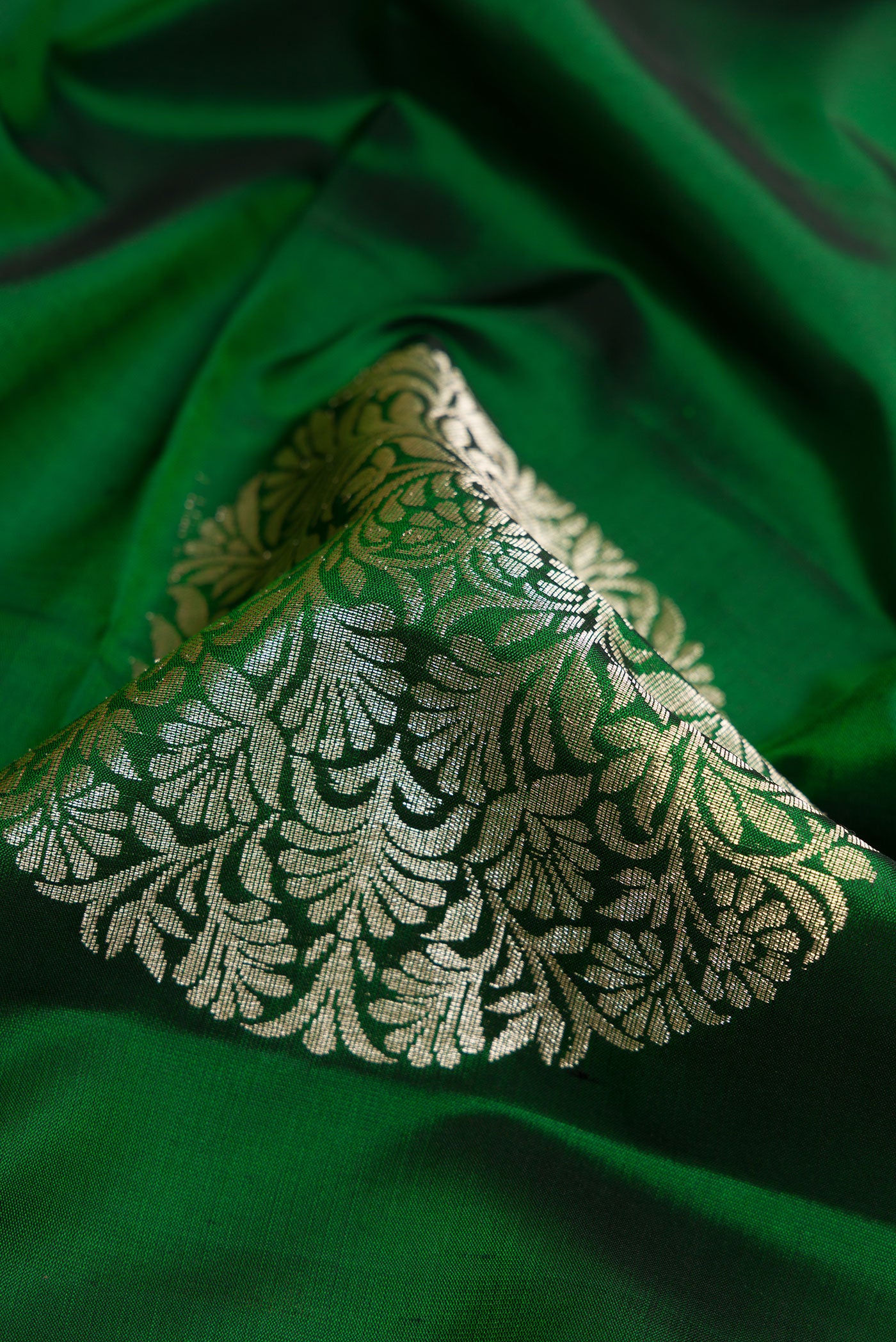 Close up of Green Dual Tone Soft Silk Saree with Zari Butta on the body and Plain Border.  displaying folds