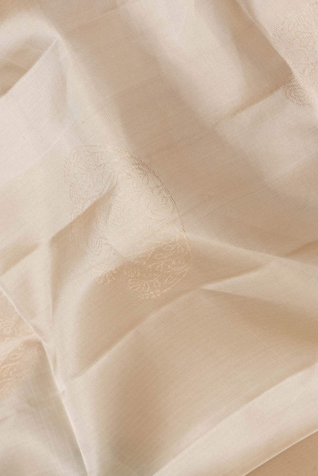Close up of Beige Dual Tone Soft Silk Saree with Zari Butta on the body and Zari Border.  displaying folds