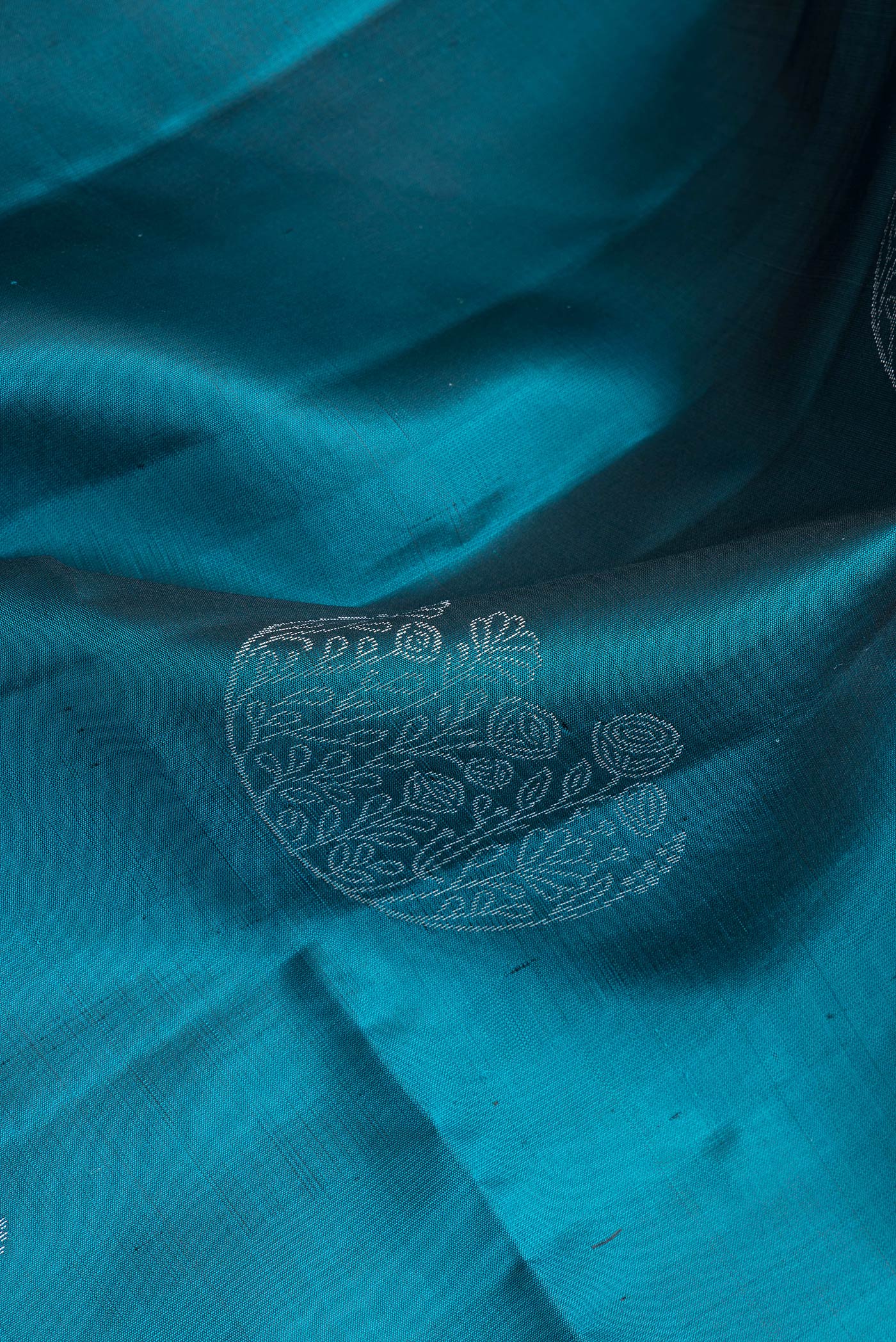 Close up of Peacock Blue Dual Tone Soft Silk Saree with Zari Butta on the body and Zari Border.  displaying folds