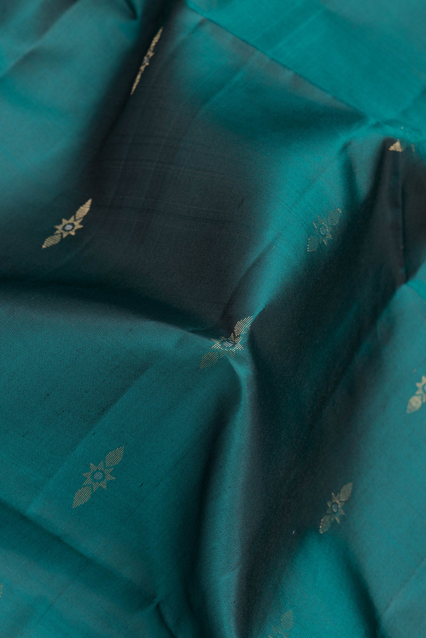 Close up of Bottle Green Dual Tone Soft Silk Saree with Zari Butta on the body and Zari Border.  displaying folds
