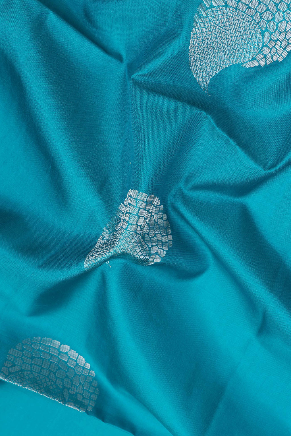 Close up of Peacock Blue Soft Silk Saree with Zari Butta on the body and Zari Border.  displaying folds
