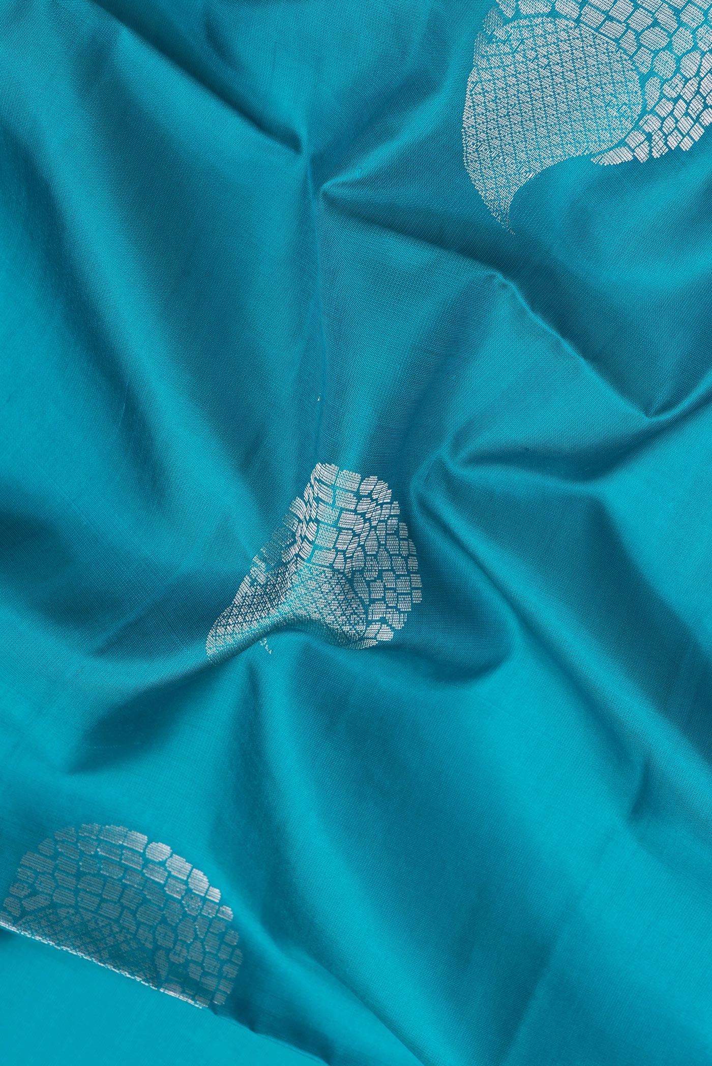 Close up of Peacock Blue Soft Silk Saree with Zari Butta on the body and Zari Border.  displaying folds