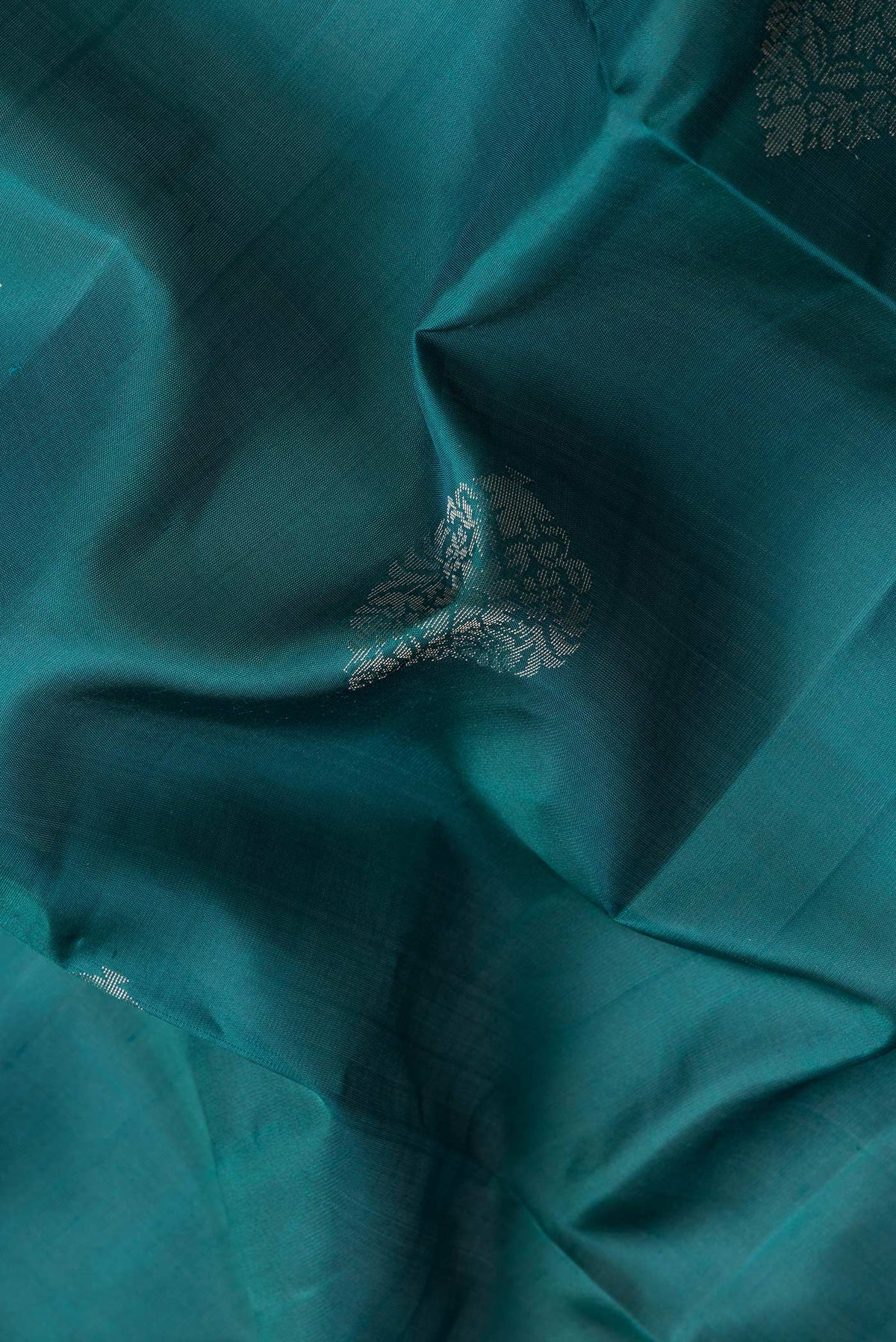 Close up of Green Dual Tone Soft Silk Saree with Zari Butta on the body and Zari Border.  displaying folds