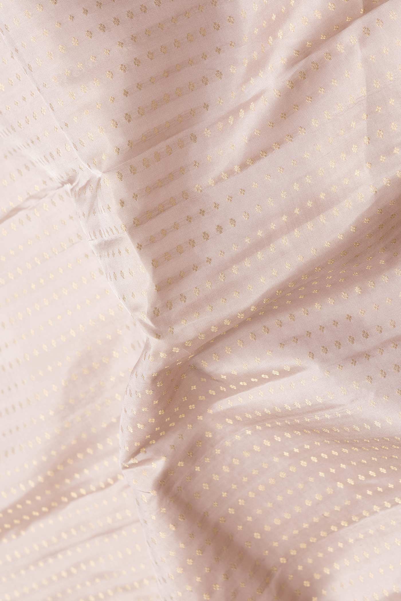 Close up of Rose Gold Dual Tone Kanchipuram Silk Saree with Zari Butta on the body and Zari Border.  displaying folds