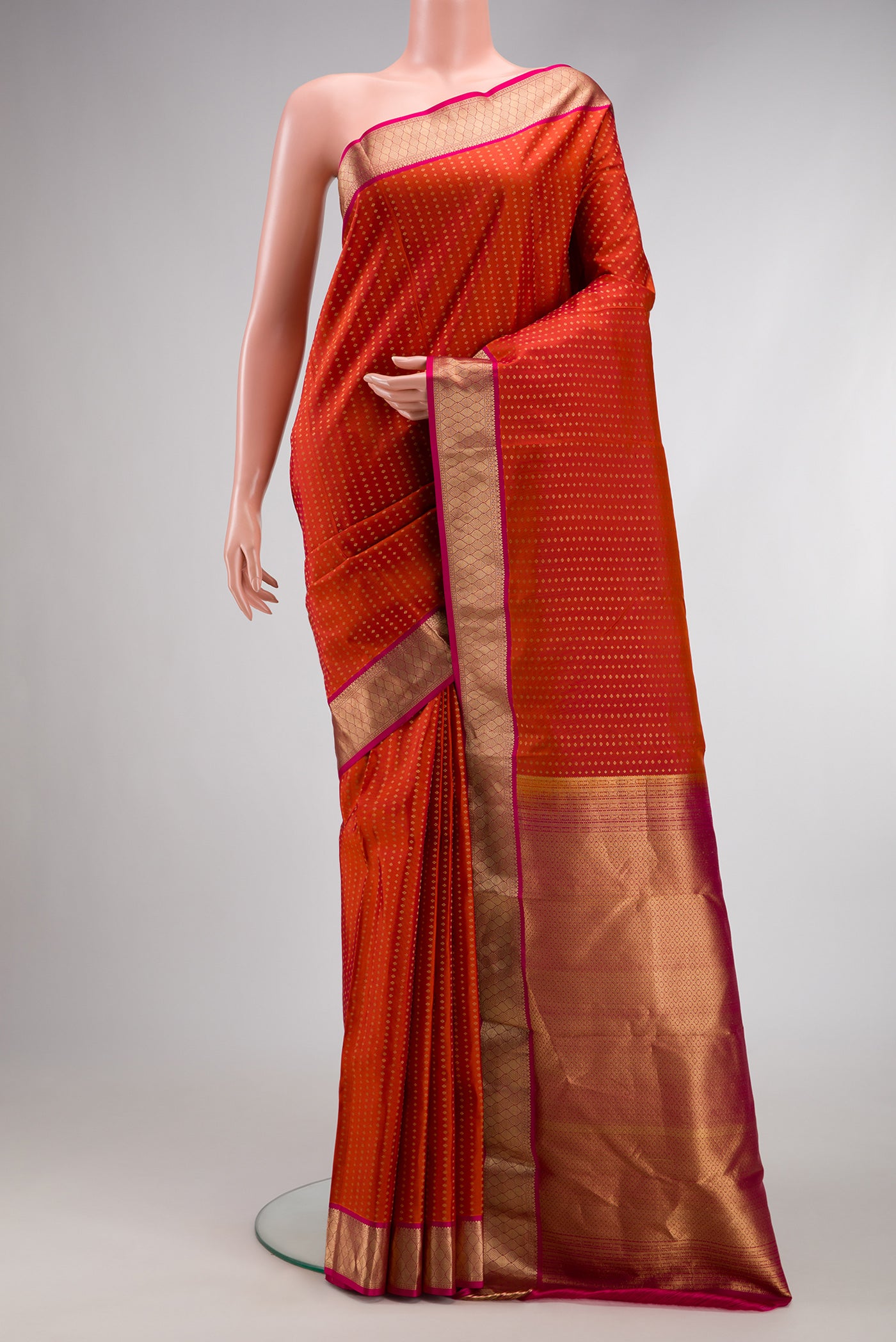 Brick Orange Dual Tone Kanchipuram Silk Saree with Stripes on the body and Zari Border.  displayed on a mannequin