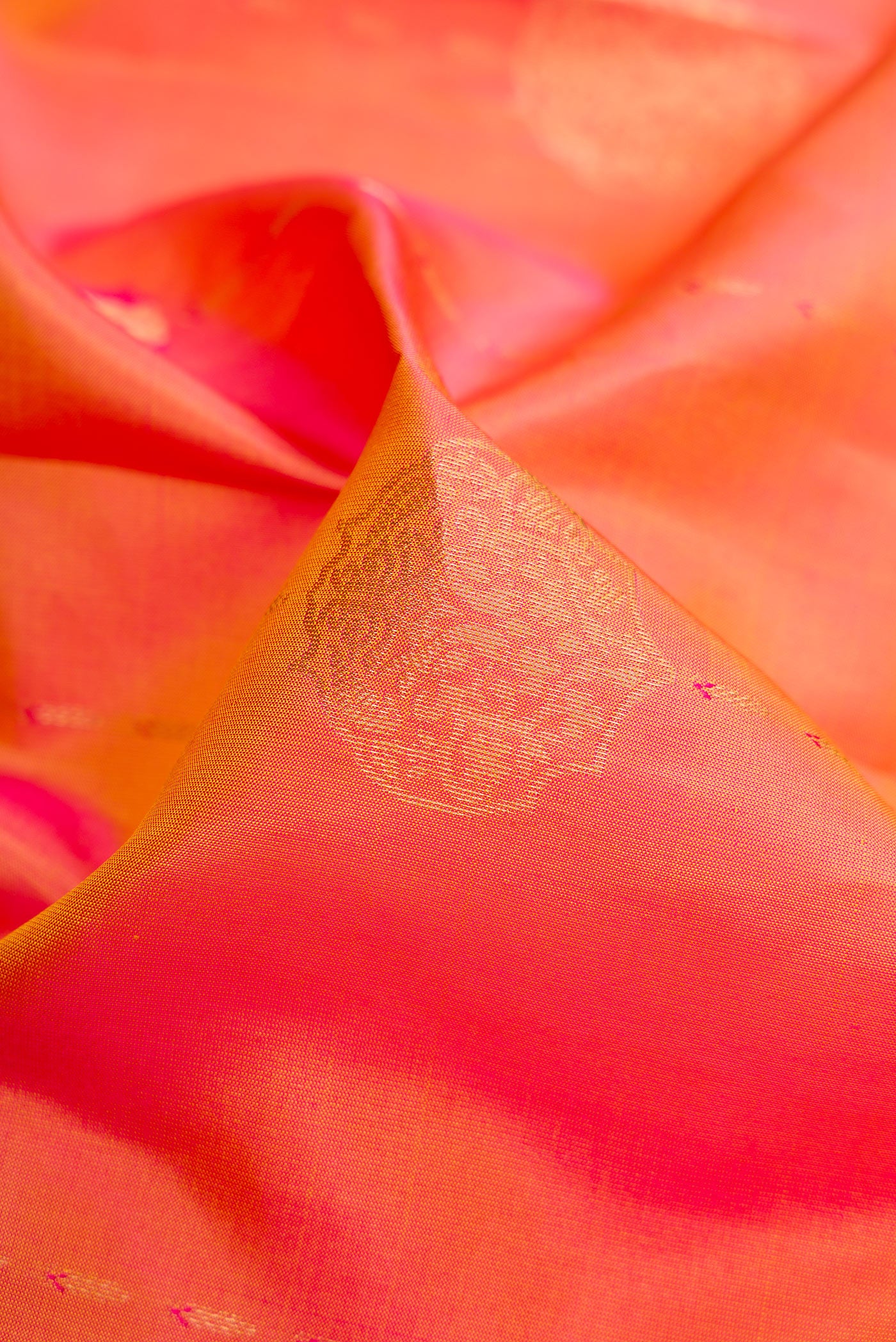 Close up of Coral Dual Tone Kanchipuram Silk Saree with Zari Butta on the body and Zari Border.  displaying folds