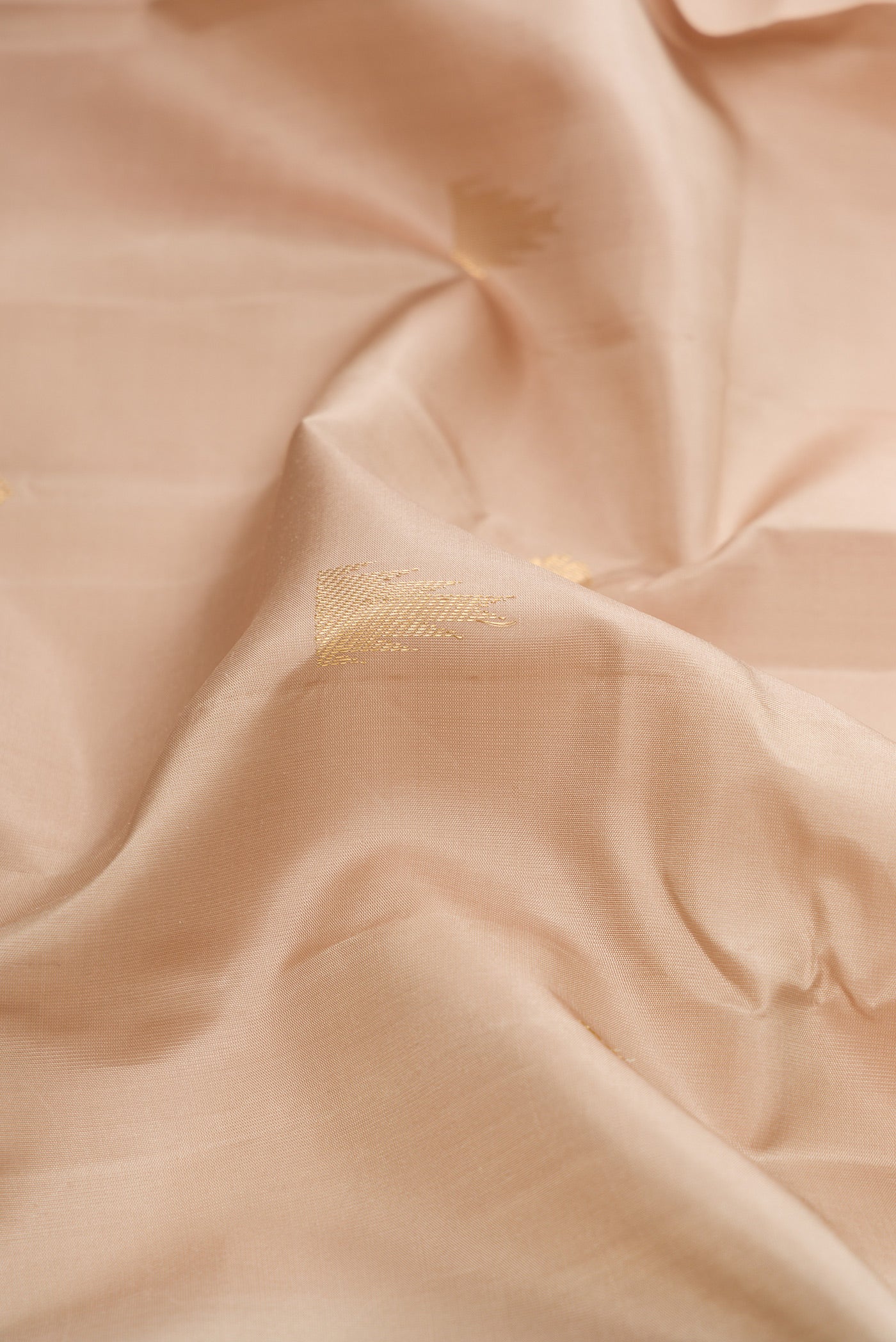 Close up of Beige Dual Tone Kanjivaram Silk Saree with Zari Butta on the body and Fancy Border.  displaying folds