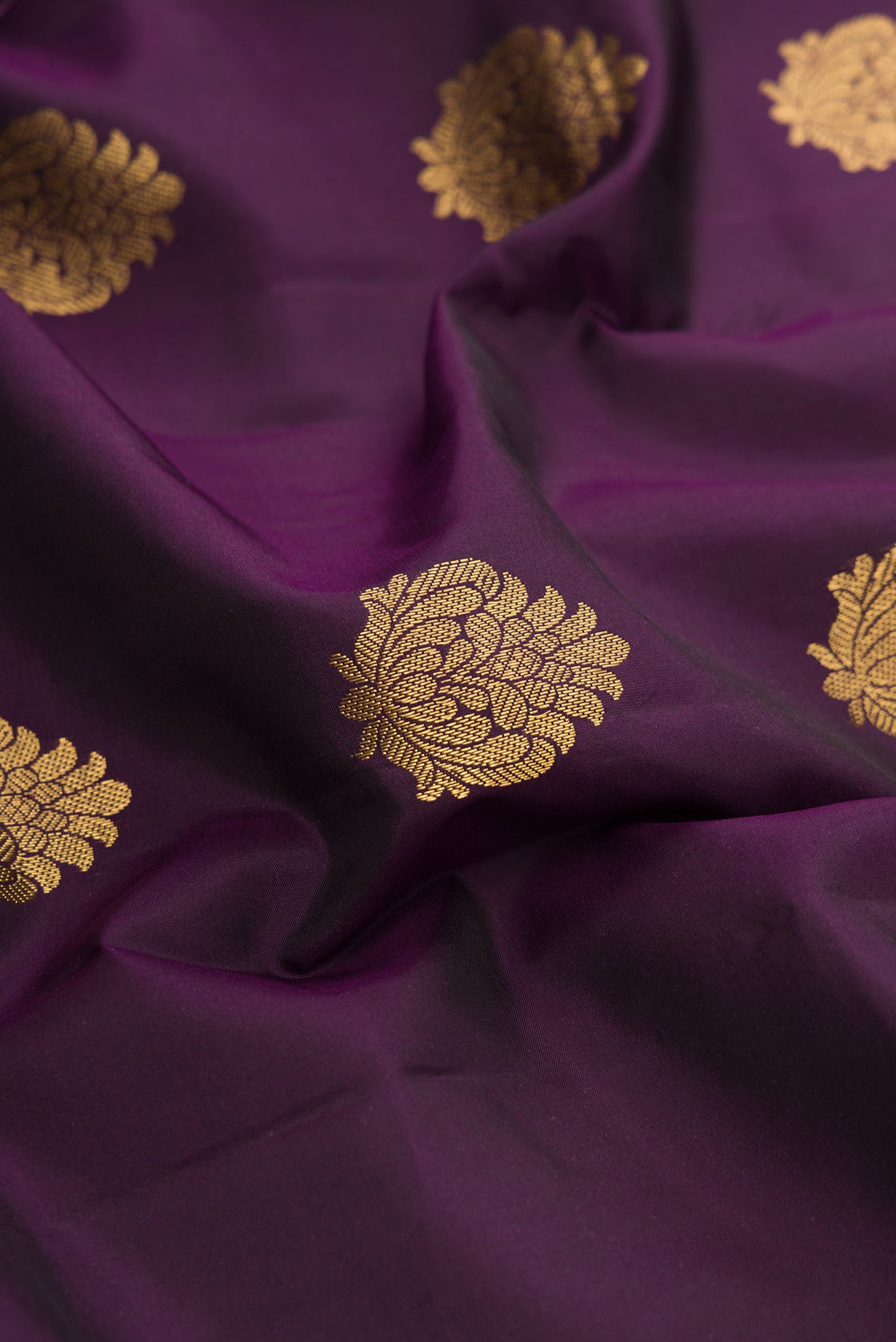 Close up of Burgundy Dual Tone Kanchipuram Silk Saree with Zari Butta on the body and Zari Border.  displaying folds