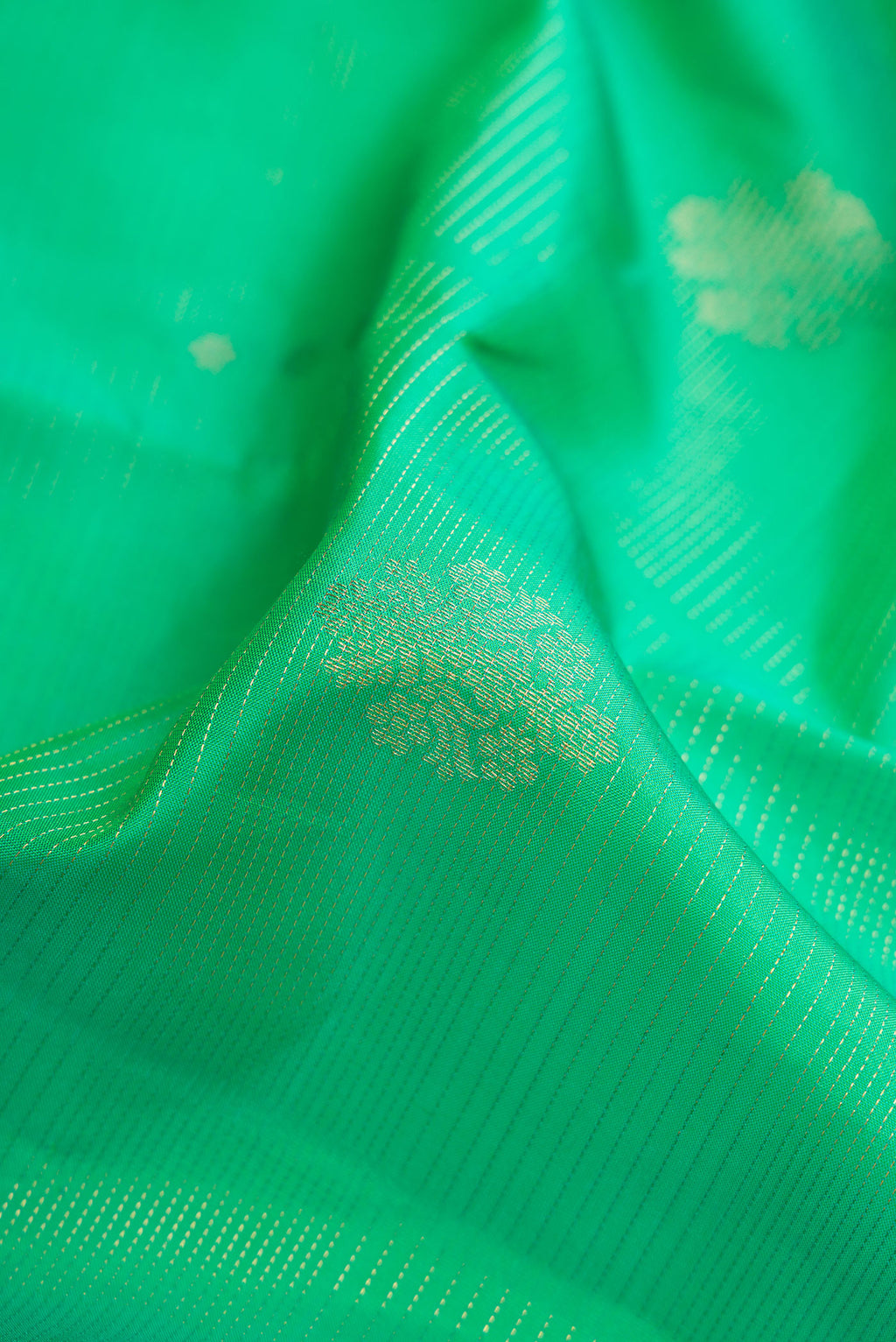 Close up of Green Dual Tone Kanjivaram Silk Saree with Zari Butta on the body and Zari Border.  displaying folds