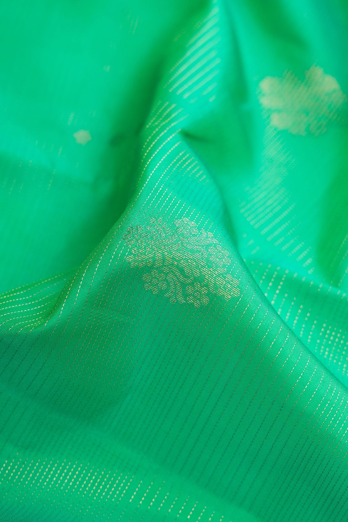 Close up of Green Dual Tone Kanjivaram Silk Saree with Zari Butta on the body and Zari Border.  displaying folds