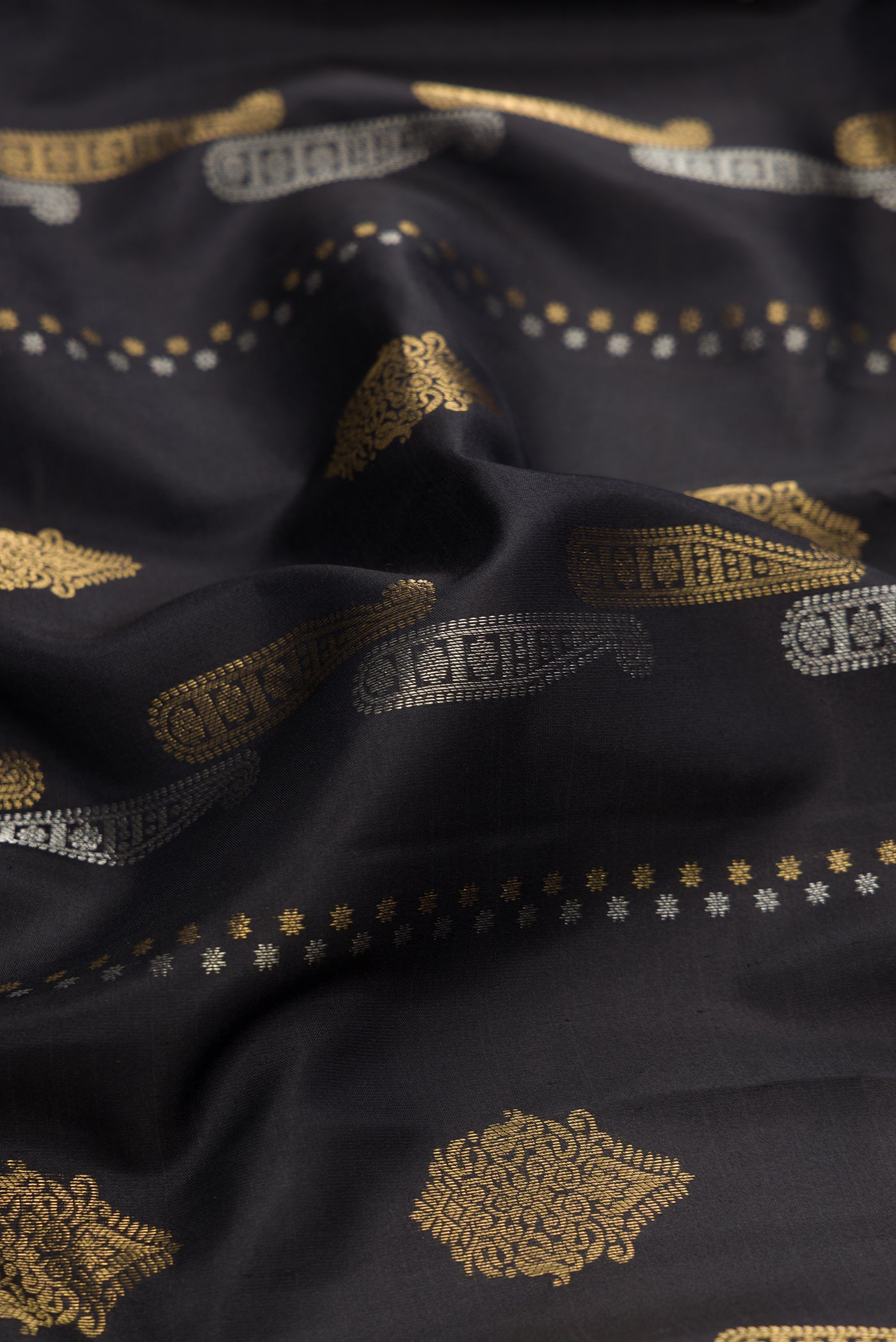 Close up of Black Dual Tone Kanjivaram Silk Saree with Zari Butta on the body and Zari Border.  displaying folds