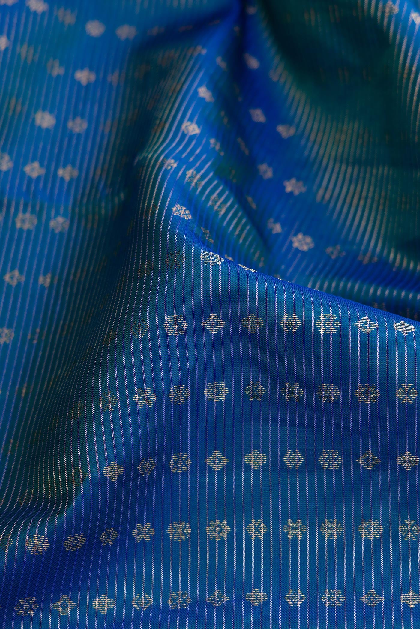 Close up of Peacock Blue Dual Tone Kanchipuram Silk Saree with Stripes on the body and Plain Border.  displaying folds
