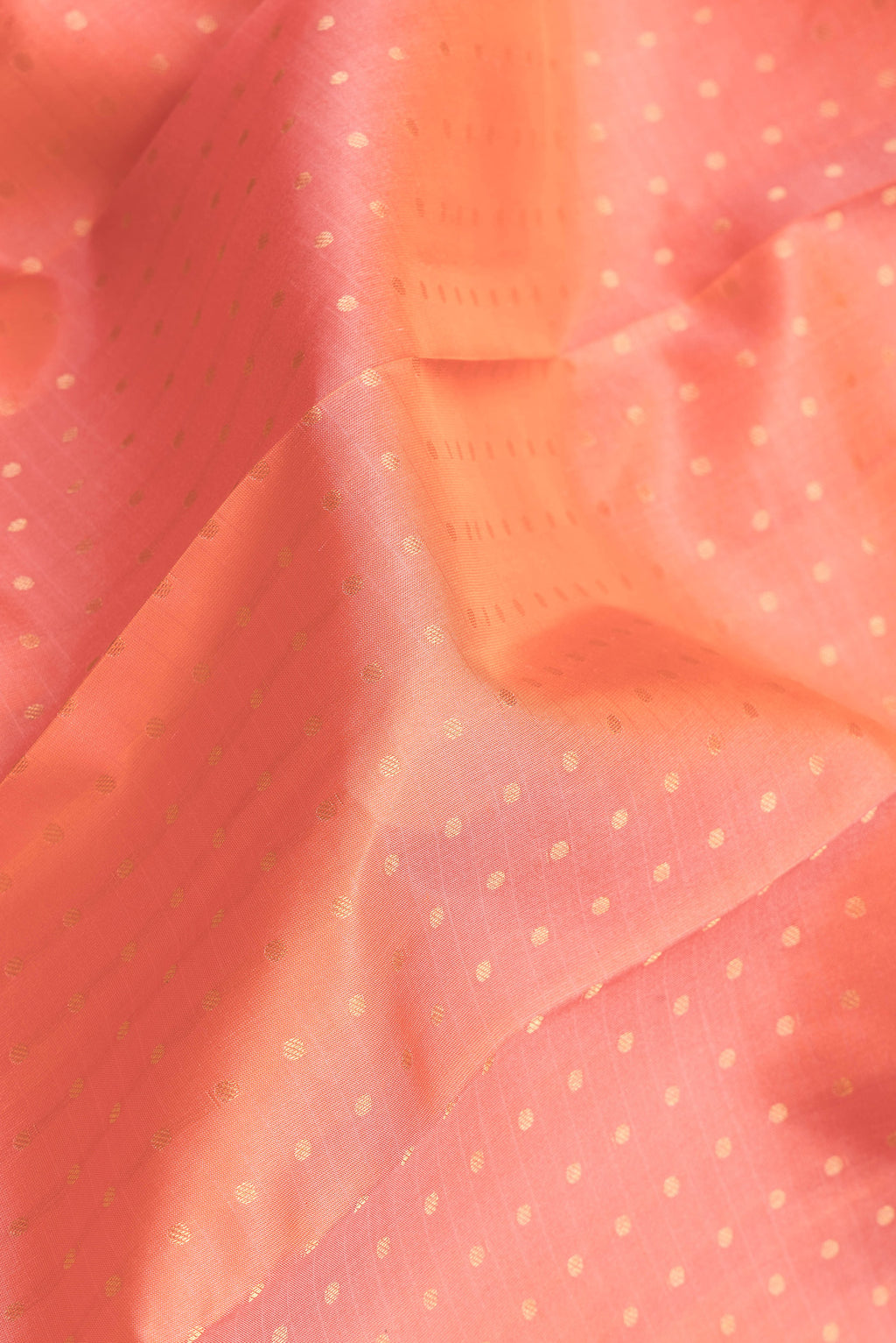 Close up of Peach Dual Tone Kanchipuram Silk Saree with Zari Butta on the body and Zari Border.  displaying folds