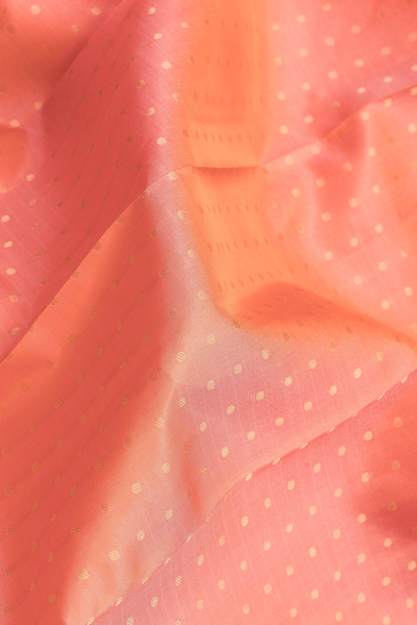 Close up of Peach Dual Tone Kanchipuram Silk Saree with Zari Butta on the body and Zari Border.  displaying folds