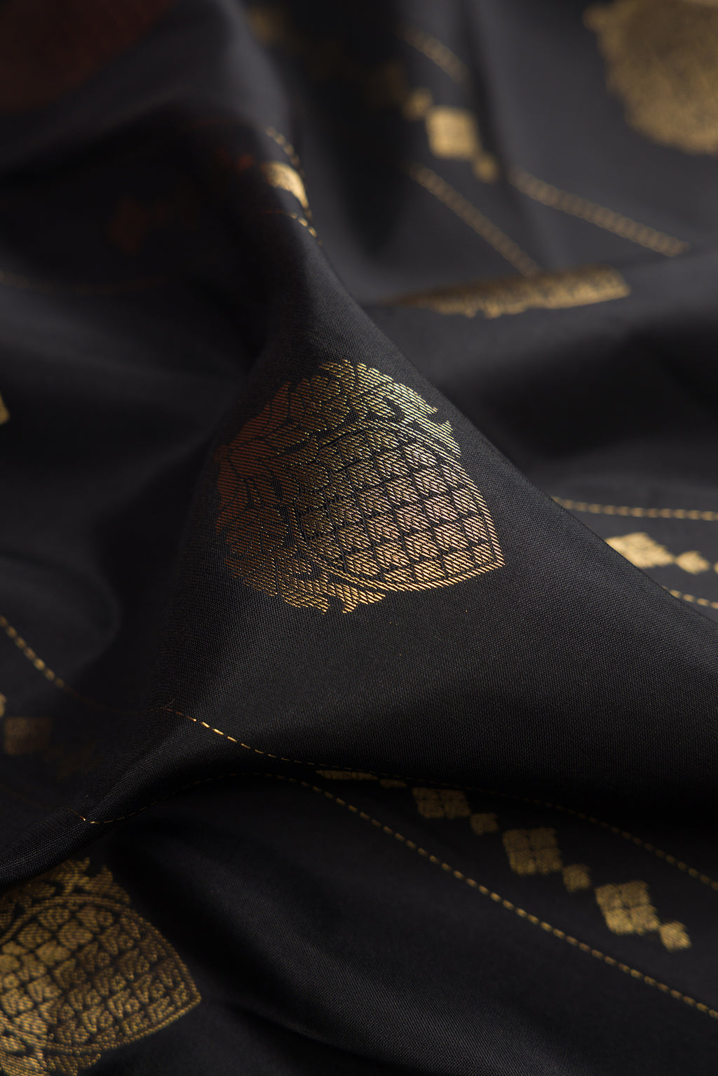 Close up of Black Dual Tone Kanchipuram Silk Saree with Zari Butta on the body and Zari Border.  displaying folds