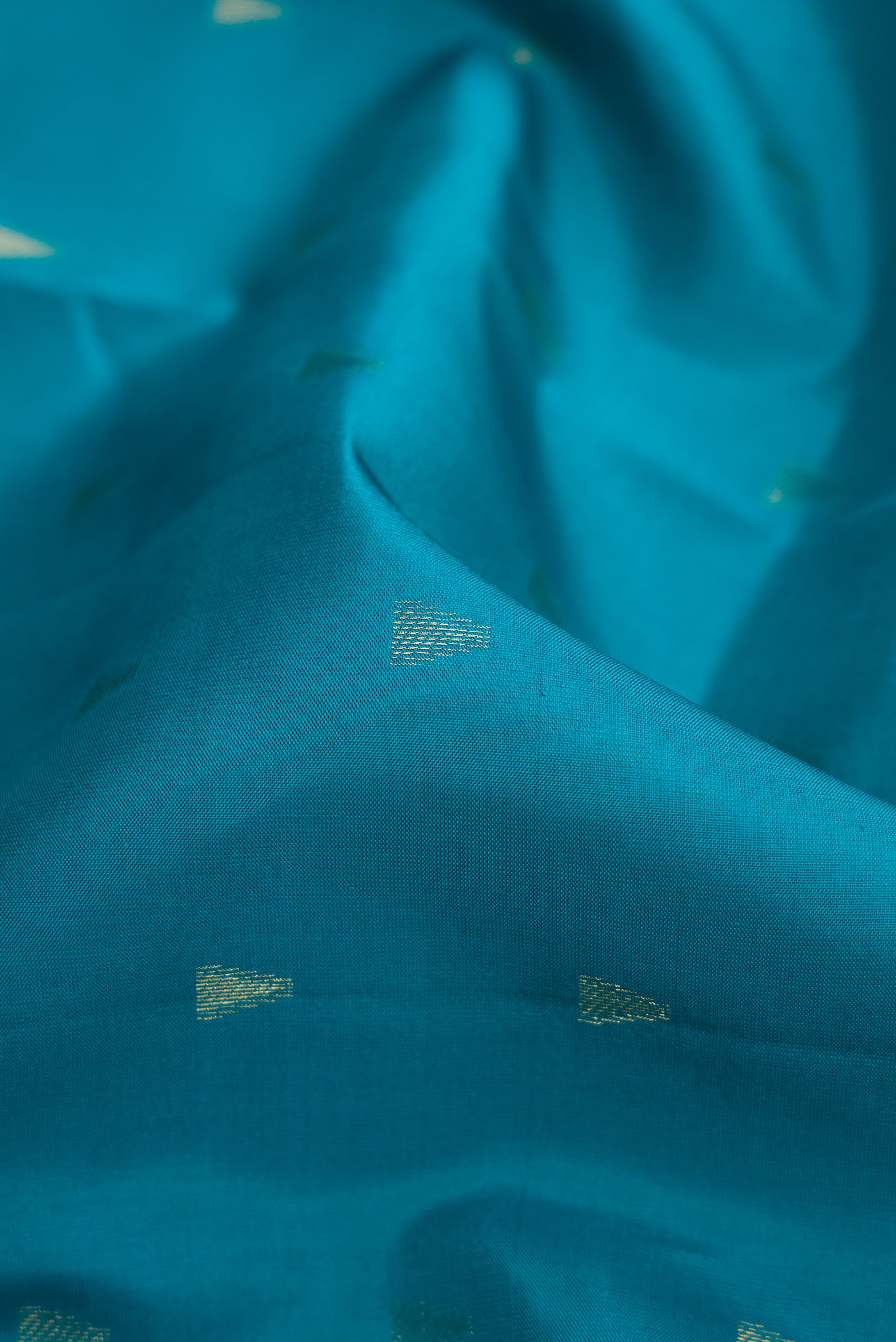Close up of Peacock Blue Dual Tone Kanchipuram Silk Saree with Zari Butta on the body and Fancy Border.  displaying folds