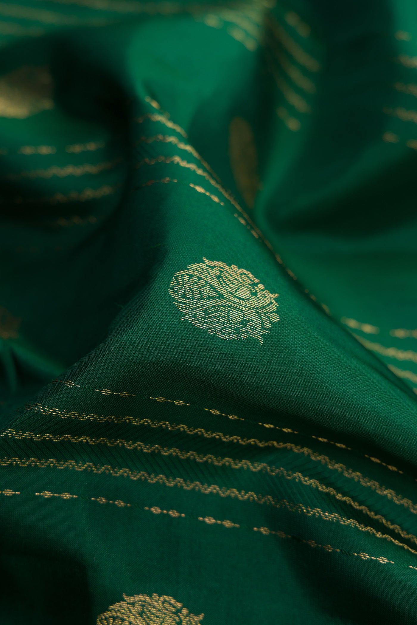 Close up of Green Dual Tone Kanchipuram Silk Saree with Stripes on the body and Zari Border.  displaying folds
