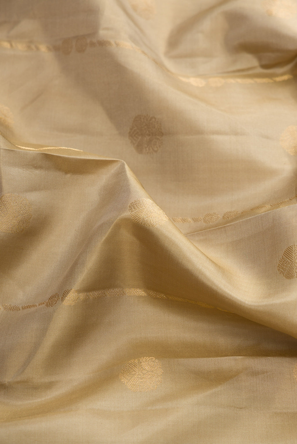 Close up of Dark Beige Dual Tone Kanchipuram Silk Saree with Zari Butta on the body and Zari Border.  displaying folds