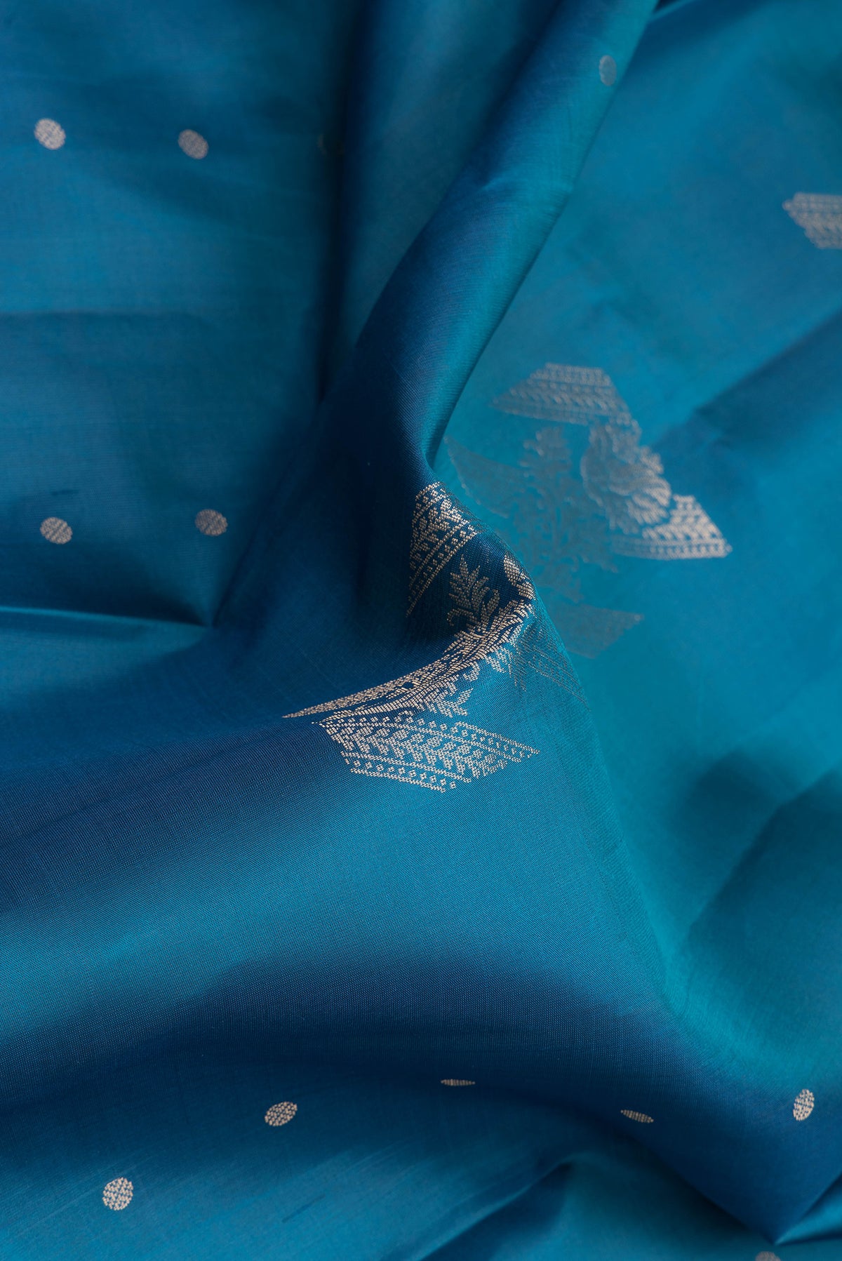 Close up of Peacock Blue Soft Silk Saree with Zari Butta on the body and Without Border.  displaying folds