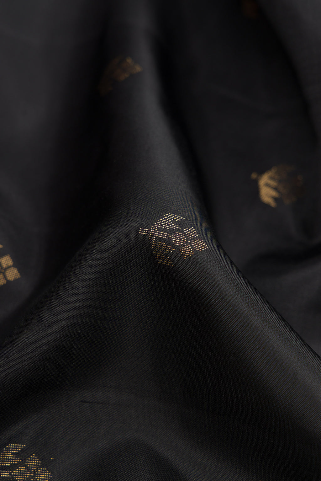 Close up of Black Dual Tone Soft Silk Saree with Zari Butta on the body and Zari Border.  displaying folds