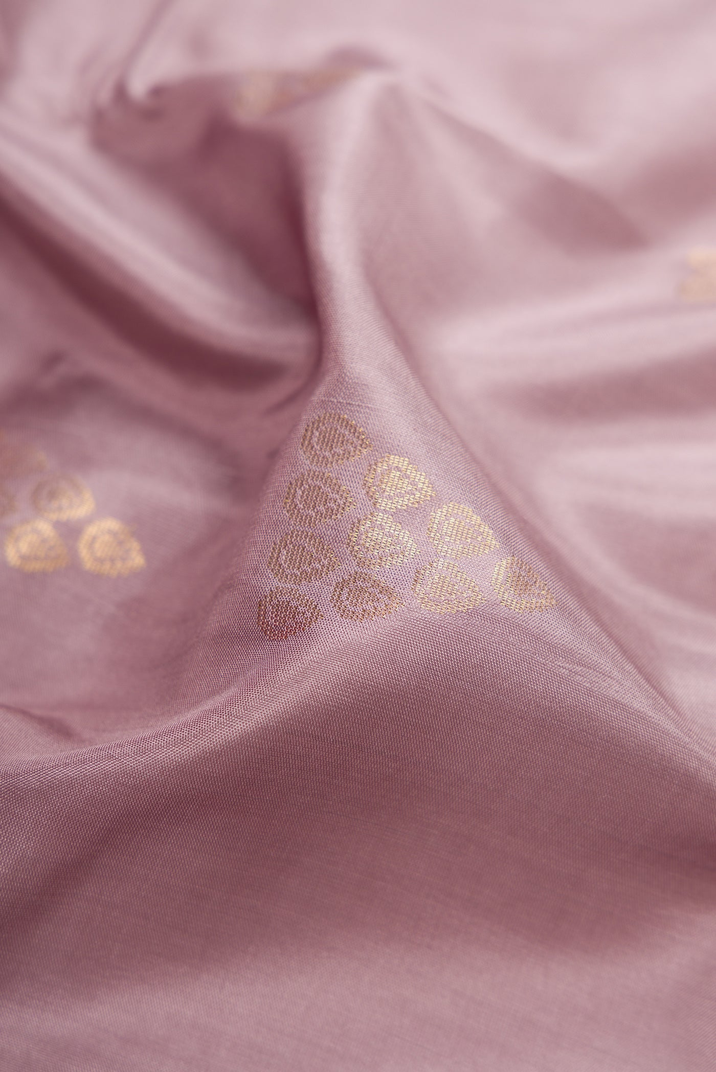 Close up of Rose Gold Dual Tone Soft Silk Saree with Zari Butta on the body and Zari Border.  displaying folds