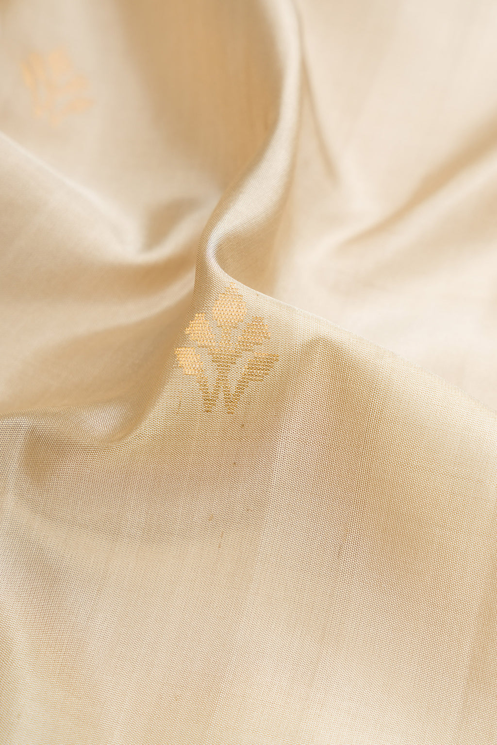 Close up of Beige Dual Tone Soft Silk Saree with Zari Butta on the body and Zari Border.  displaying folds
