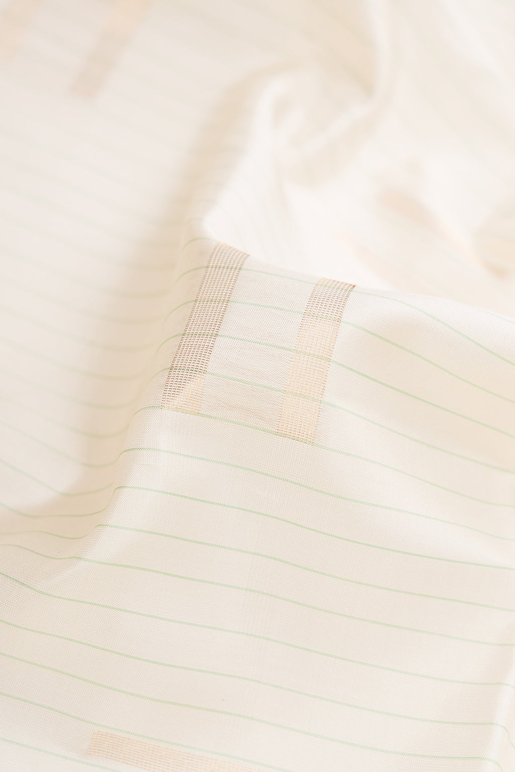 Close up of Off White Dual Tone Soft Silk Saree with Zari Butta on the body and Fancy Border.  displaying folds