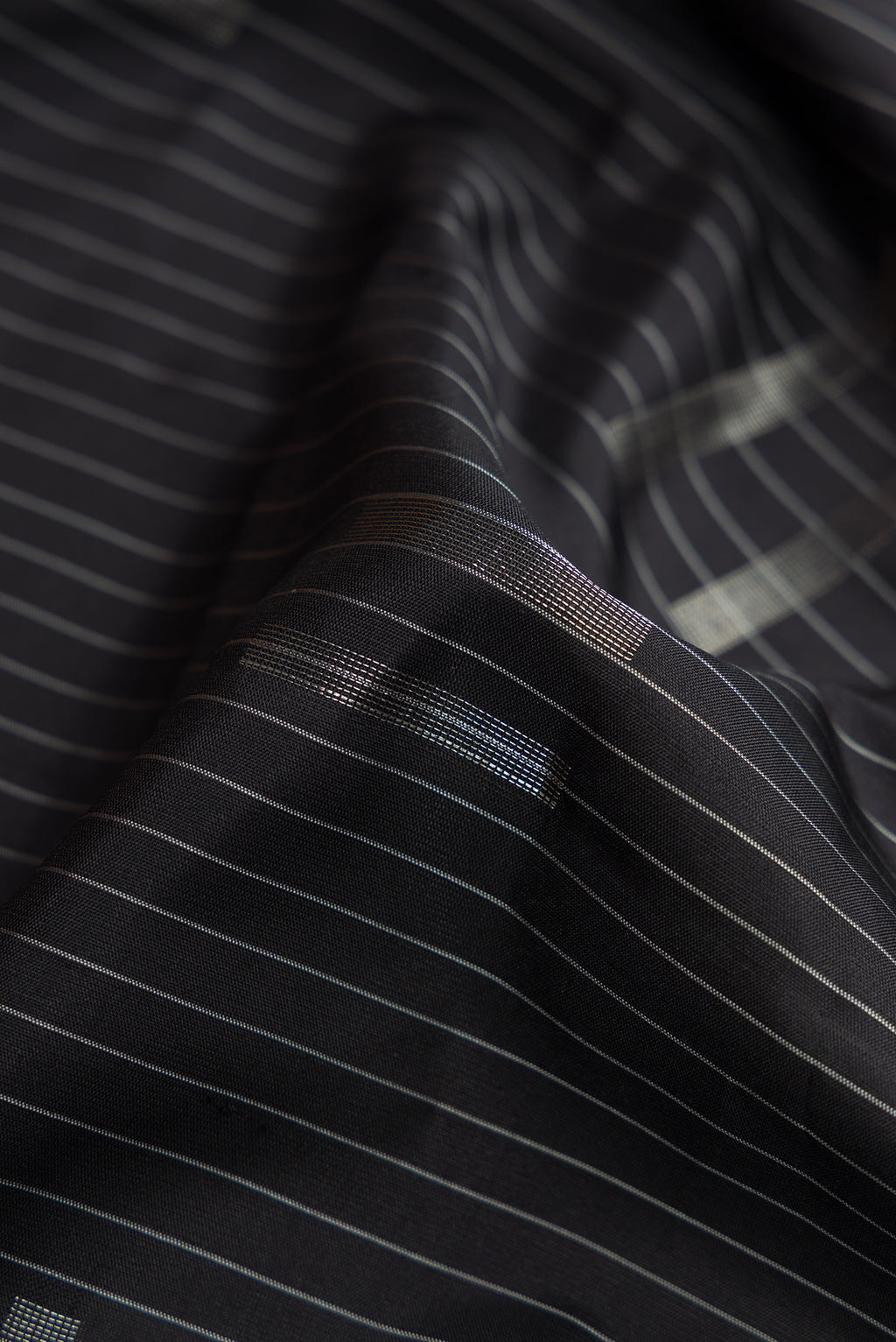 Close up of Black Dual Tone Soft Silk Saree with Stripes on the body and Zari Border.  displaying folds