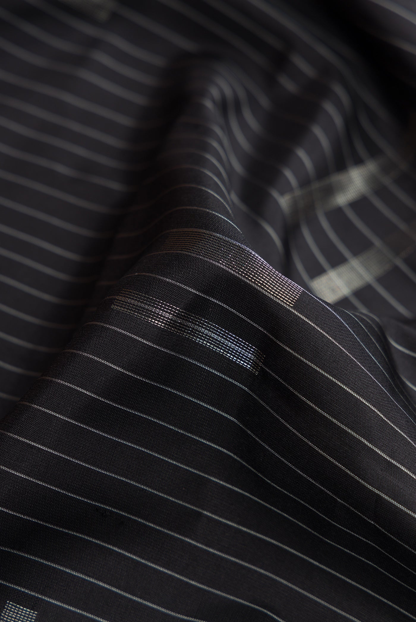 Close up of Black Dual Tone Soft Silk Saree with Stripes on the body and Zari Border.  displaying folds