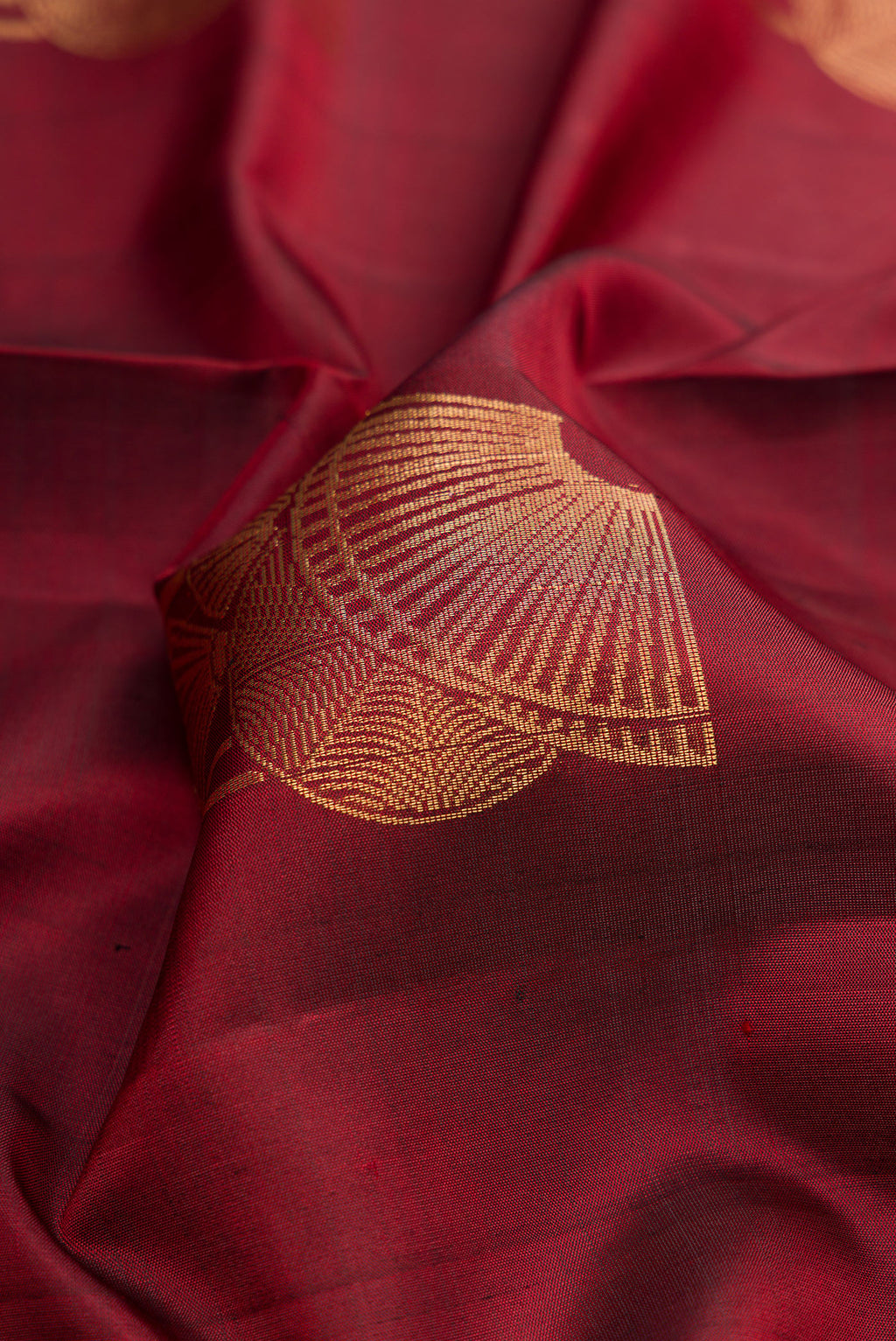 Close up of Maroon Dual Tone Soft Silk Saree with Zari Butta on the body and Zari Border.  displaying folds