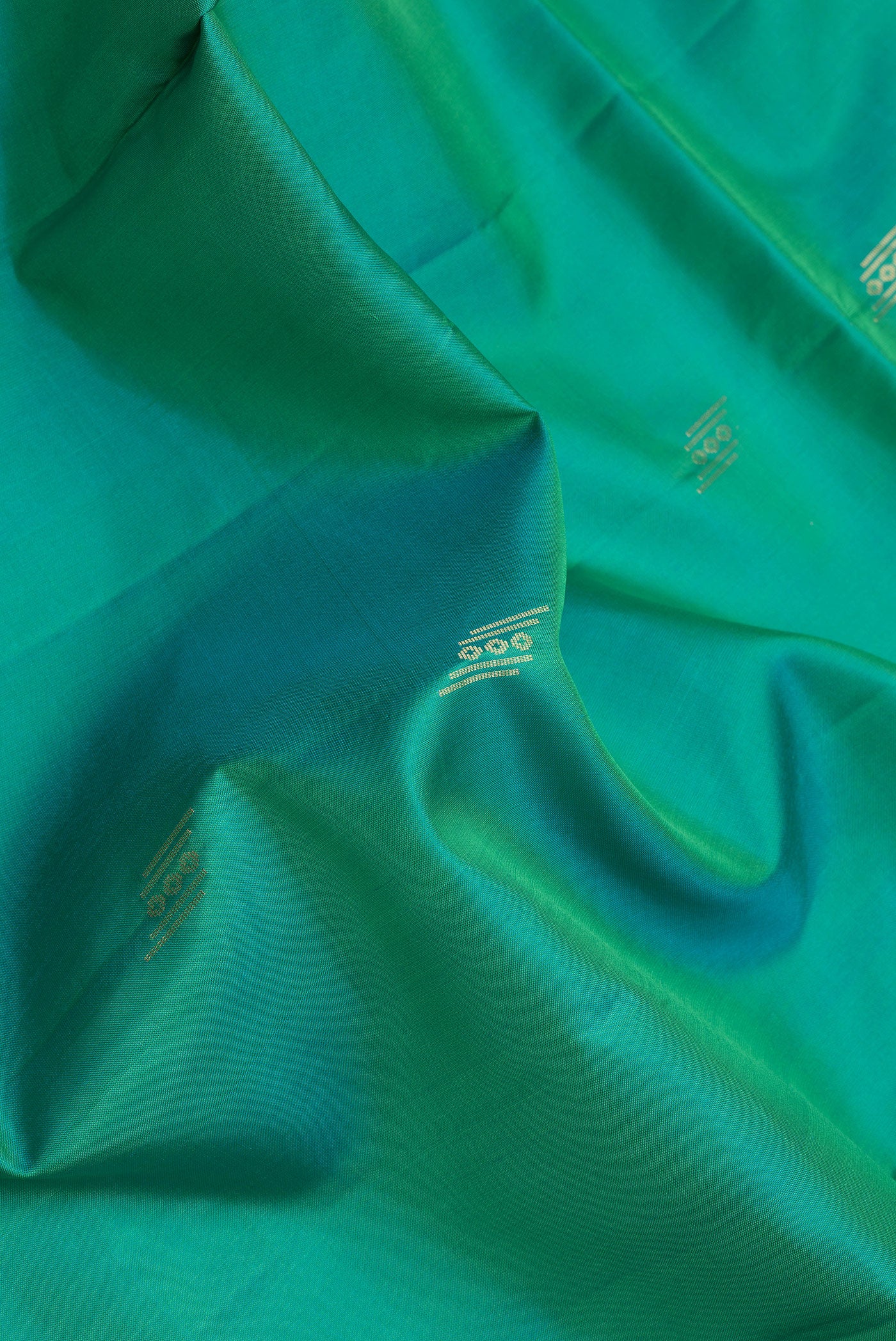 Close up of Sea Green Dual Tone Soft Silk Saree with Zari Butta on the body and Zari Border.  displaying folds