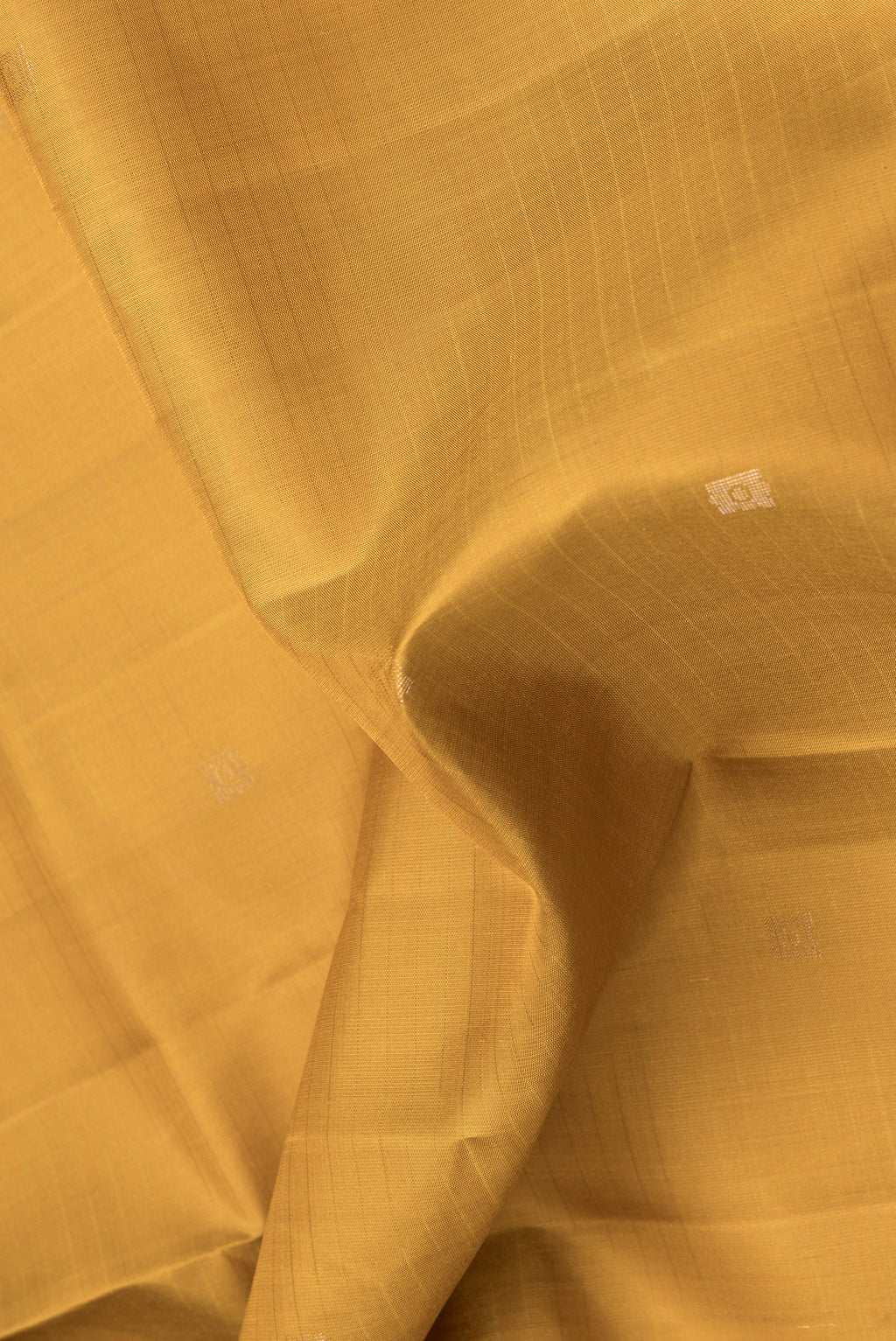 Close up of Mustard Dual Tone Soft Silk Saree with Zari Butta on the body and Zari Border.  displaying folds
