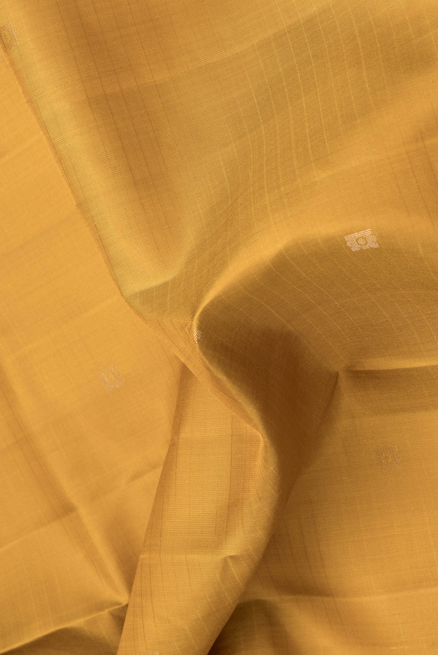 Close up of Mustard Dual Tone Soft Silk Saree with Zari Butta on the body and Zari Border.  displaying folds