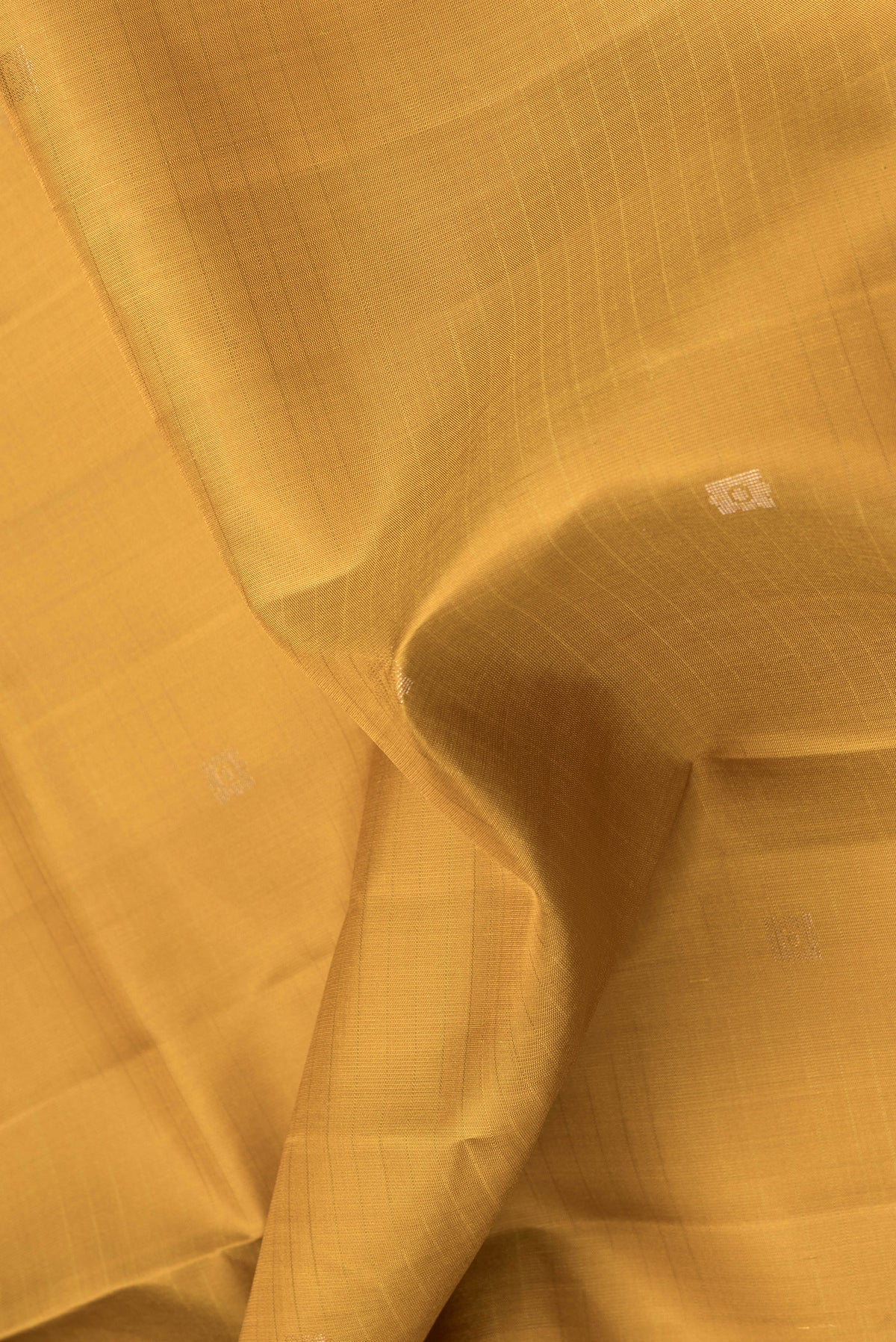 Close up of Mustard Dual Tone Soft Silk Saree with Zari Butta on the body and Zari Border.  displaying folds