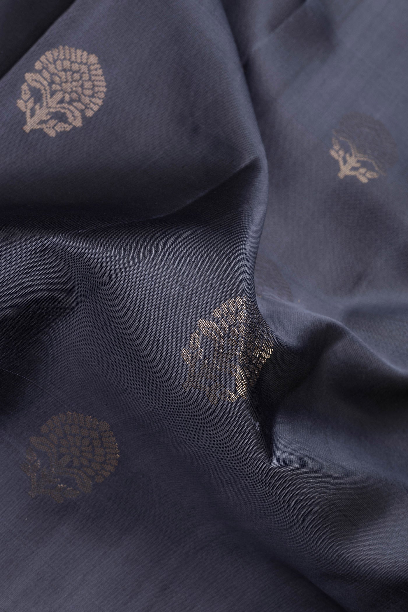 Close up of Grey Dual Tone Soft Silk Saree with Zari Butta on the body and Zari Border.  displaying folds