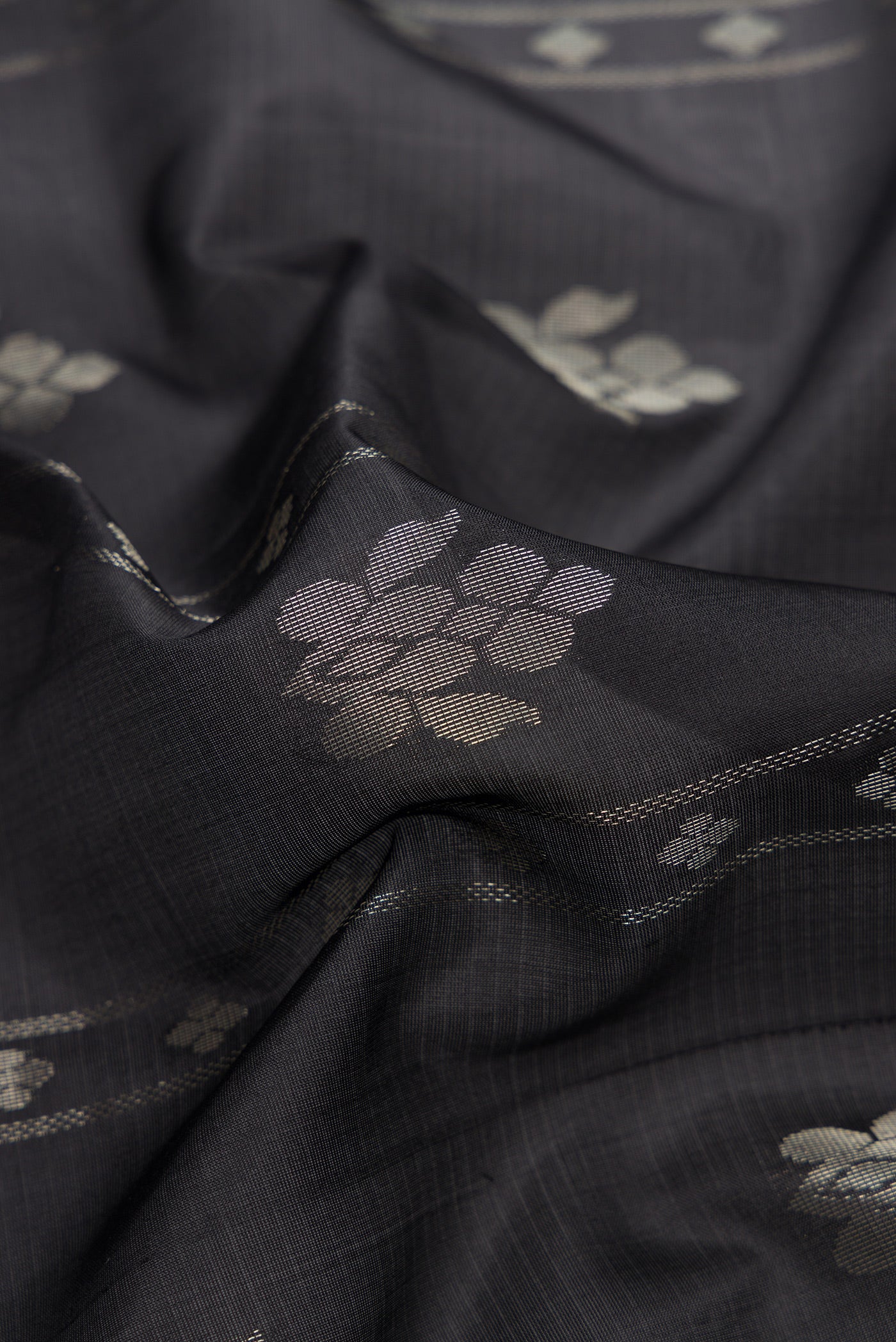 Close up of Black Dual Tone Soft Silk Saree with Zari Butta on the body and Zari Border.  displaying folds