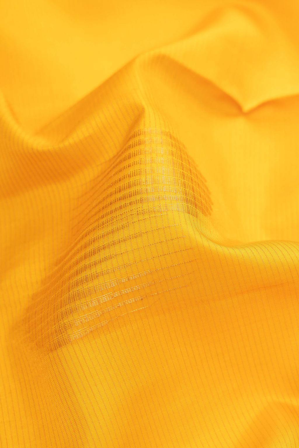Close up of Yellow Soft Silk Saree with Stripes on the body and Zari Border.  displaying folds