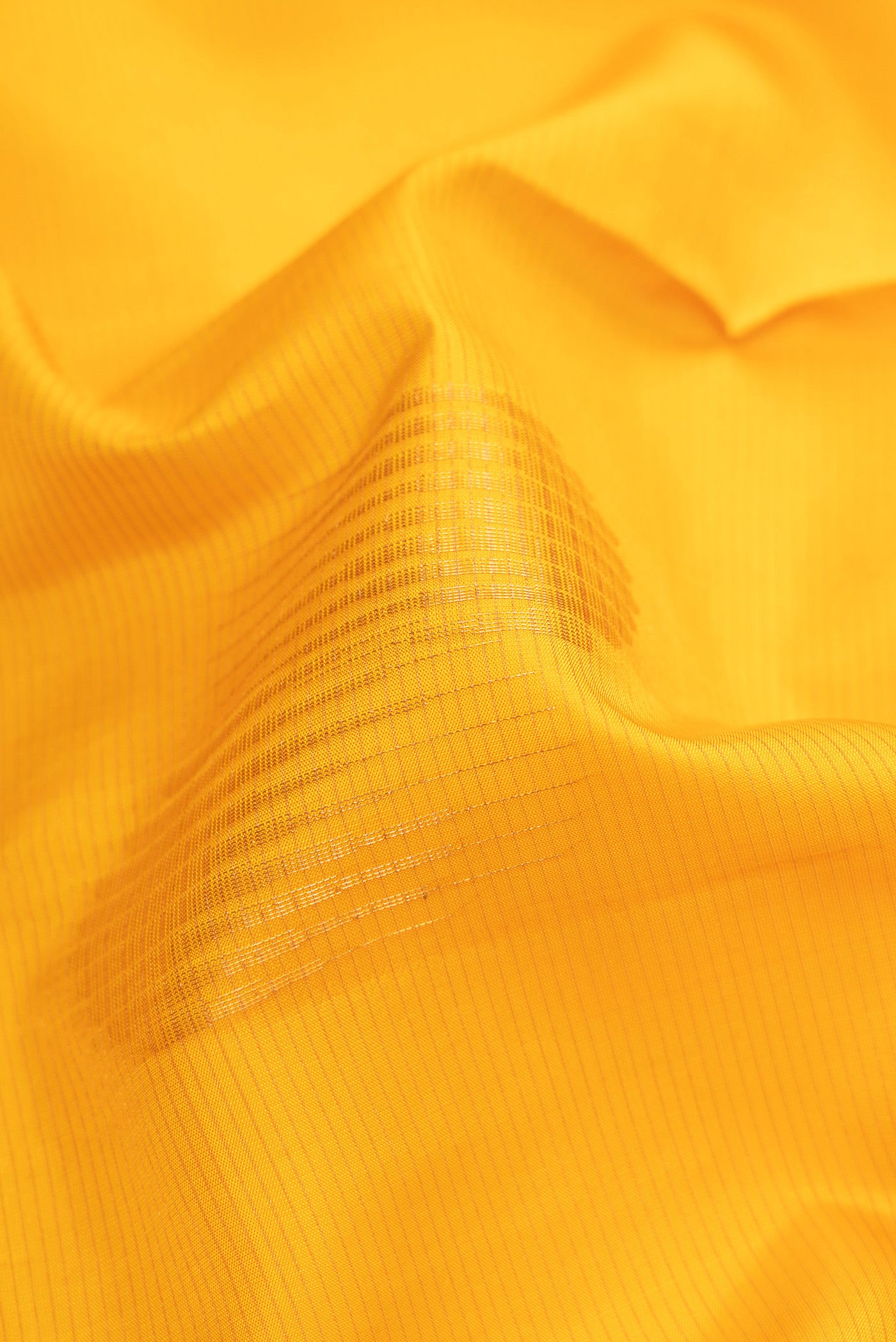 Close up of Yellow Soft Silk Saree with Stripes on the body and Zari Border.  displaying folds