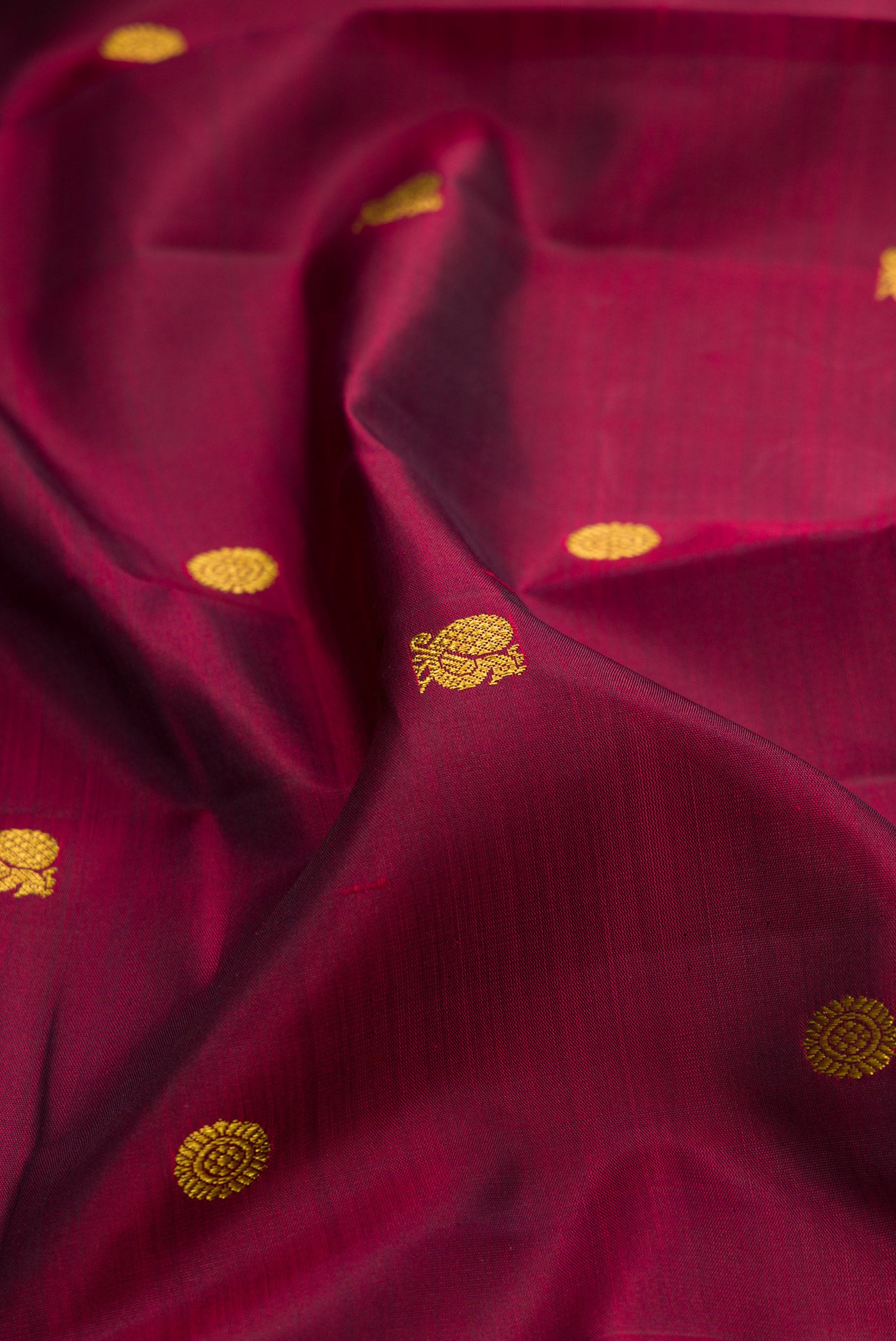 Close up of Maroon Kanjivaram Silk Saree with Zari Butta on the body and Zari Border.  displaying folds