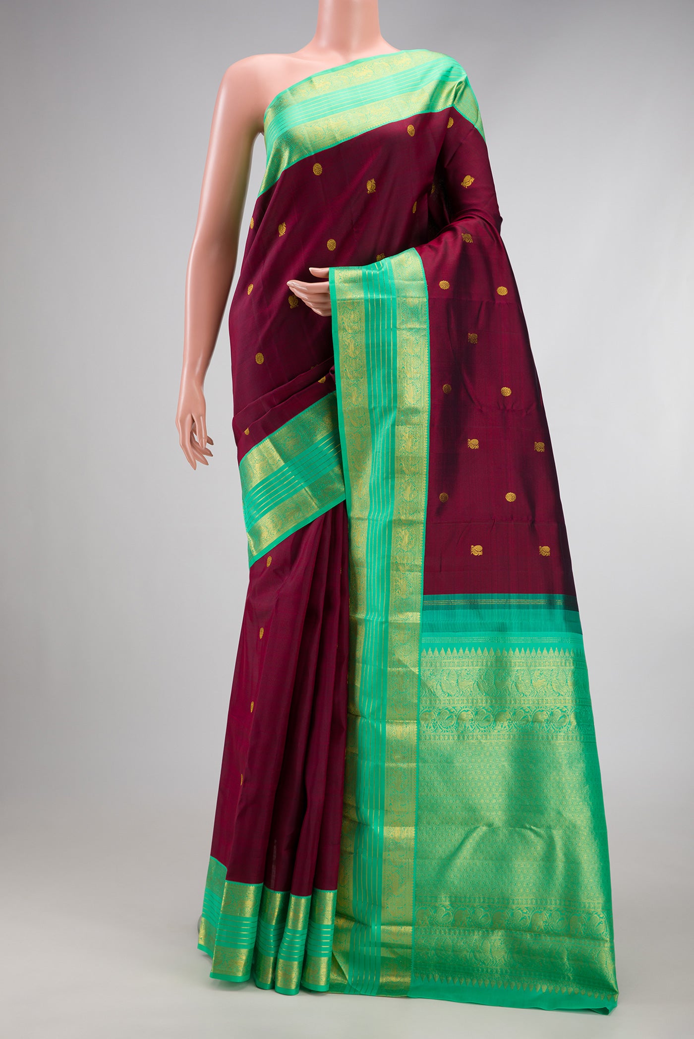 Maroon Kanjivaram Silk Saree with Zari Butta on the body and Zari Border.  displayed on a mannequin