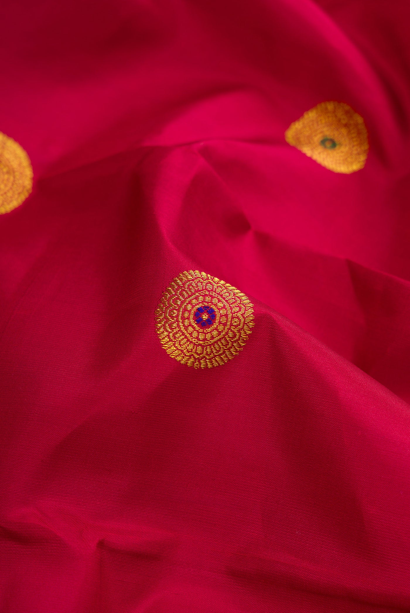 Close up of Maroon Kanchipuram Silk Saree with Zari And Thread Butta on the body and Thin Zari Line.  displaying folds