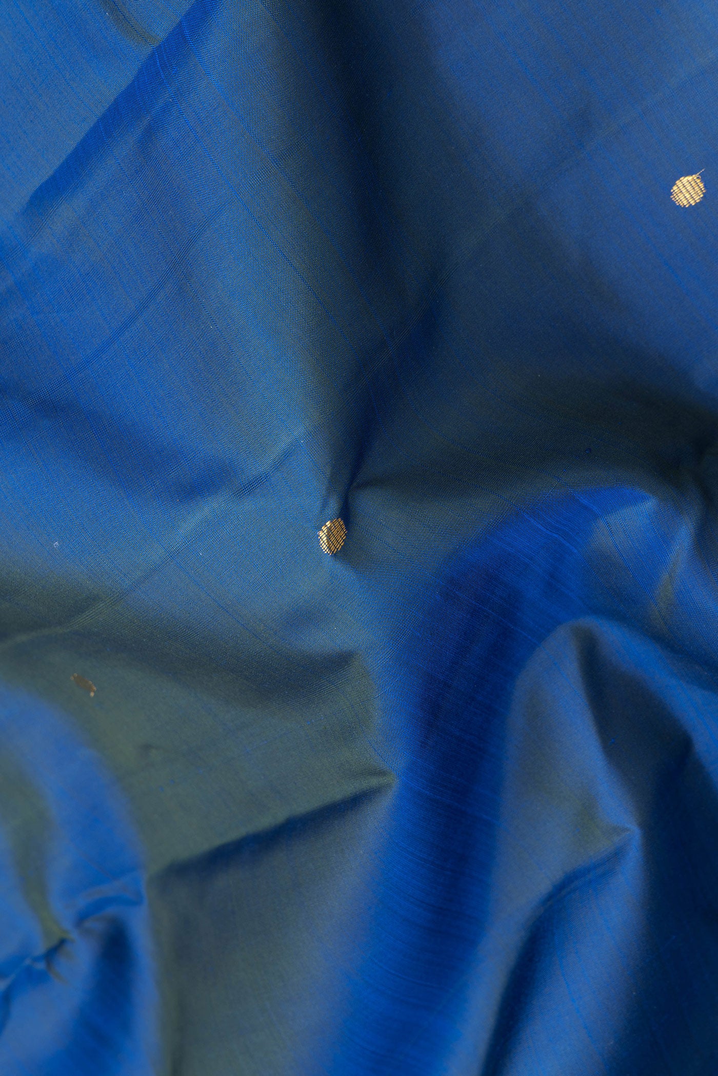 Close up of Peacock Blue Dual Tone Kanjivaram Silk Saree with Zari Butta on the body and Zari Border.  displaying folds