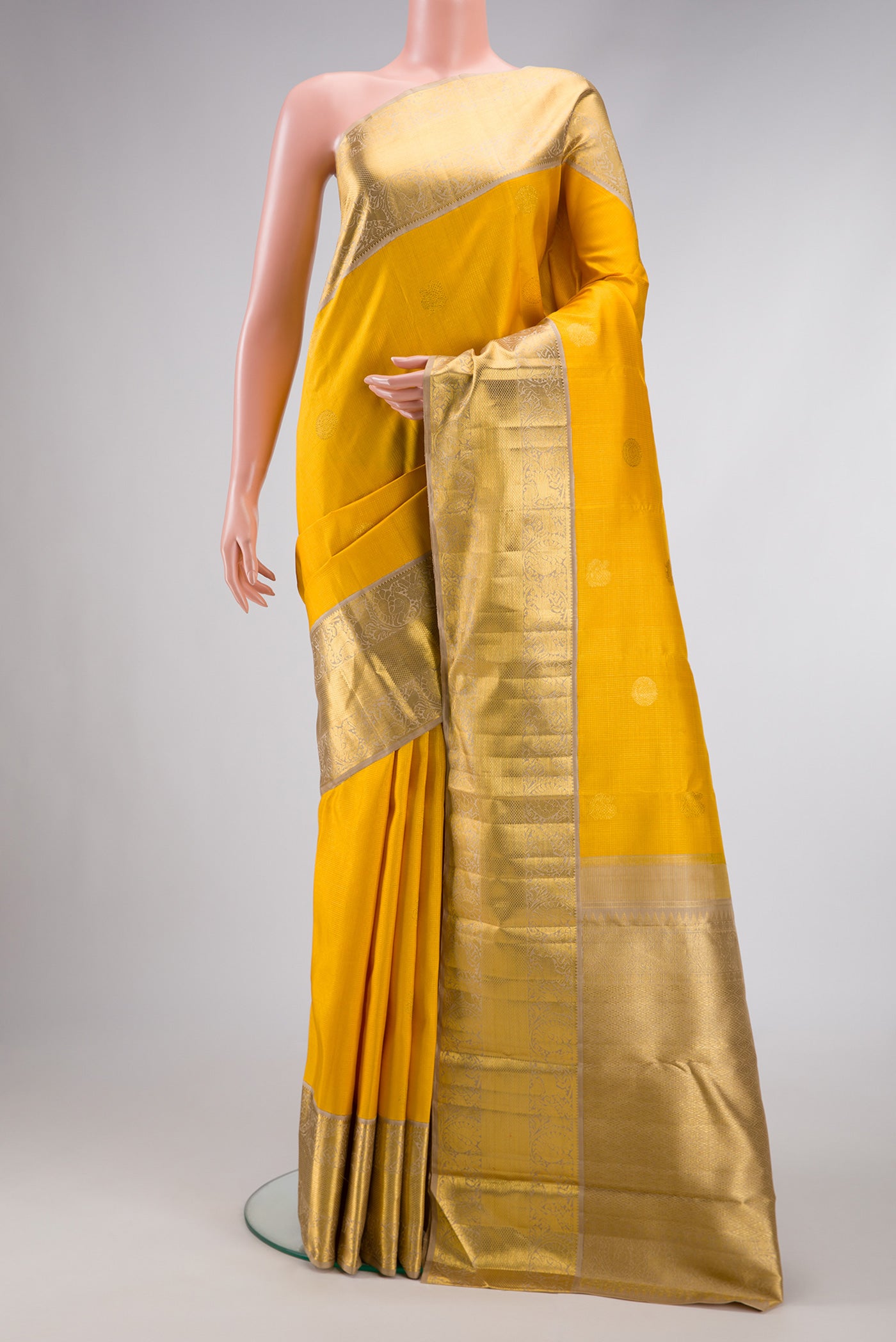 Yellow Dual Tone Kanchipuram Silk Saree with Zari Butta on the body and Zari Border.  displayed on a mannequin