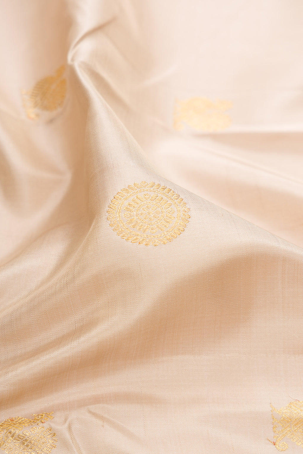 Close up of Beige Kanchipuram Silk Saree with Zari Butta on the body and Zari Border.  displaying folds