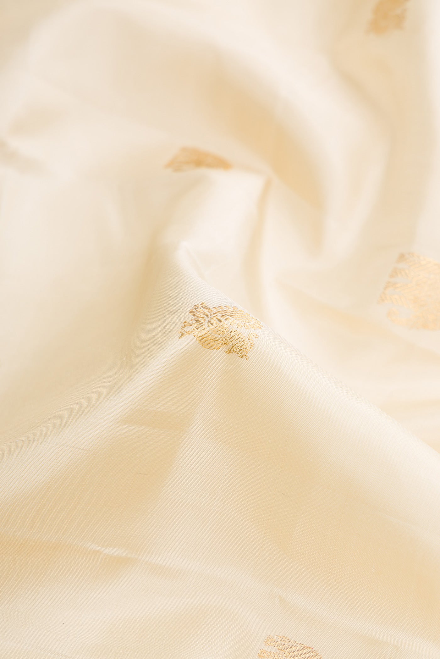 Close up of Pure Silk Pure Zari Off White Dual Tone Kanjivaram Saree with Zari Butta on the body and Zari Border.  displaying folds