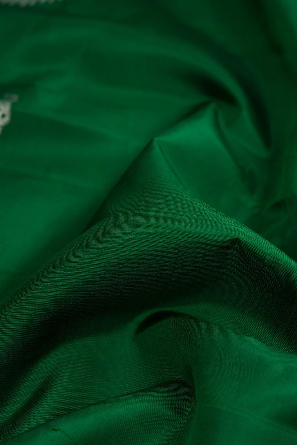 Close up of Pure Silk Pure Zari Green Dual Tone Kanjivaram Saree with Plain Body and Fancy Border.  displaying folds