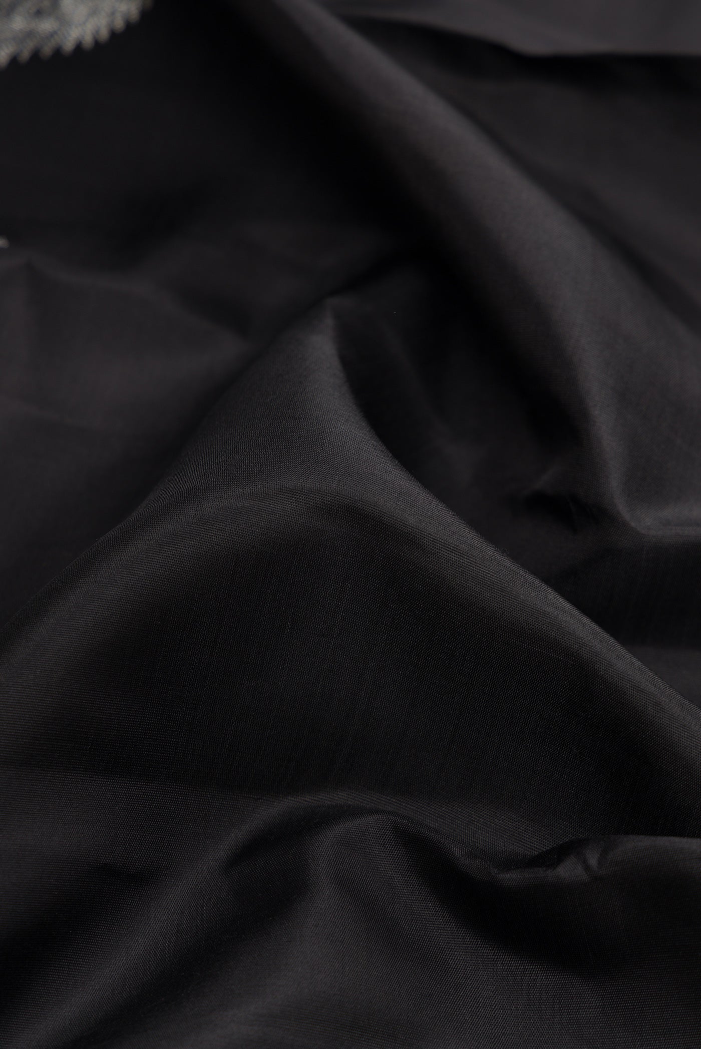 Close up of Black Dual Tone Kanjivaram Silk Saree with Plain Body and Fancy Border.  displaying folds