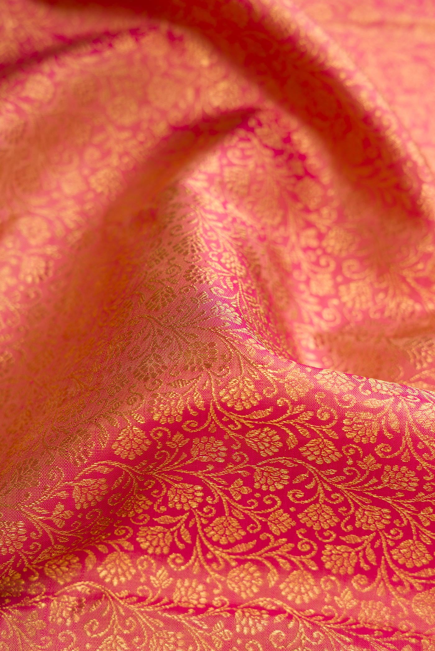 Close up of Pure Silk Pure Zari Rose Gold Dual Tone Kanjivaram Saree with Zari Brocade on the body and Zari Border.  displaying folds